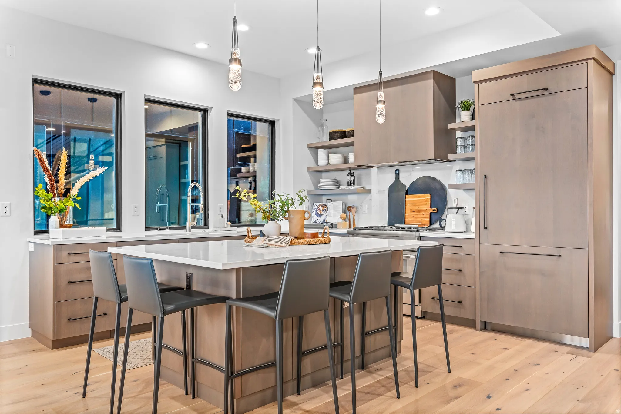 Kitchen featuring a large central island with seating, integrated appliances, wood-finish cabinetry, and extensive counter space