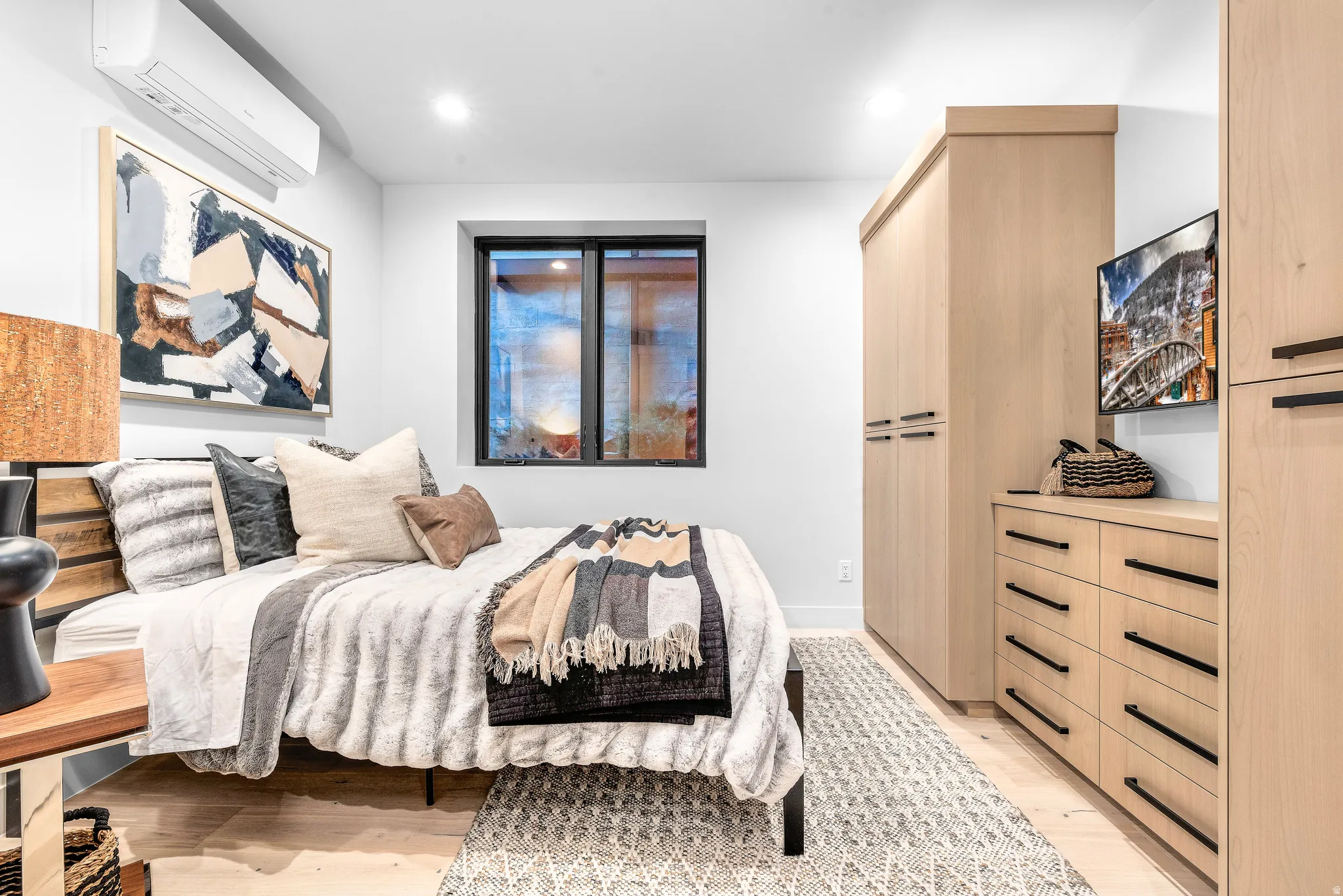 Light-toned wood-finish flooring complements the built-in cabinetry and dresser, featuring black hardware