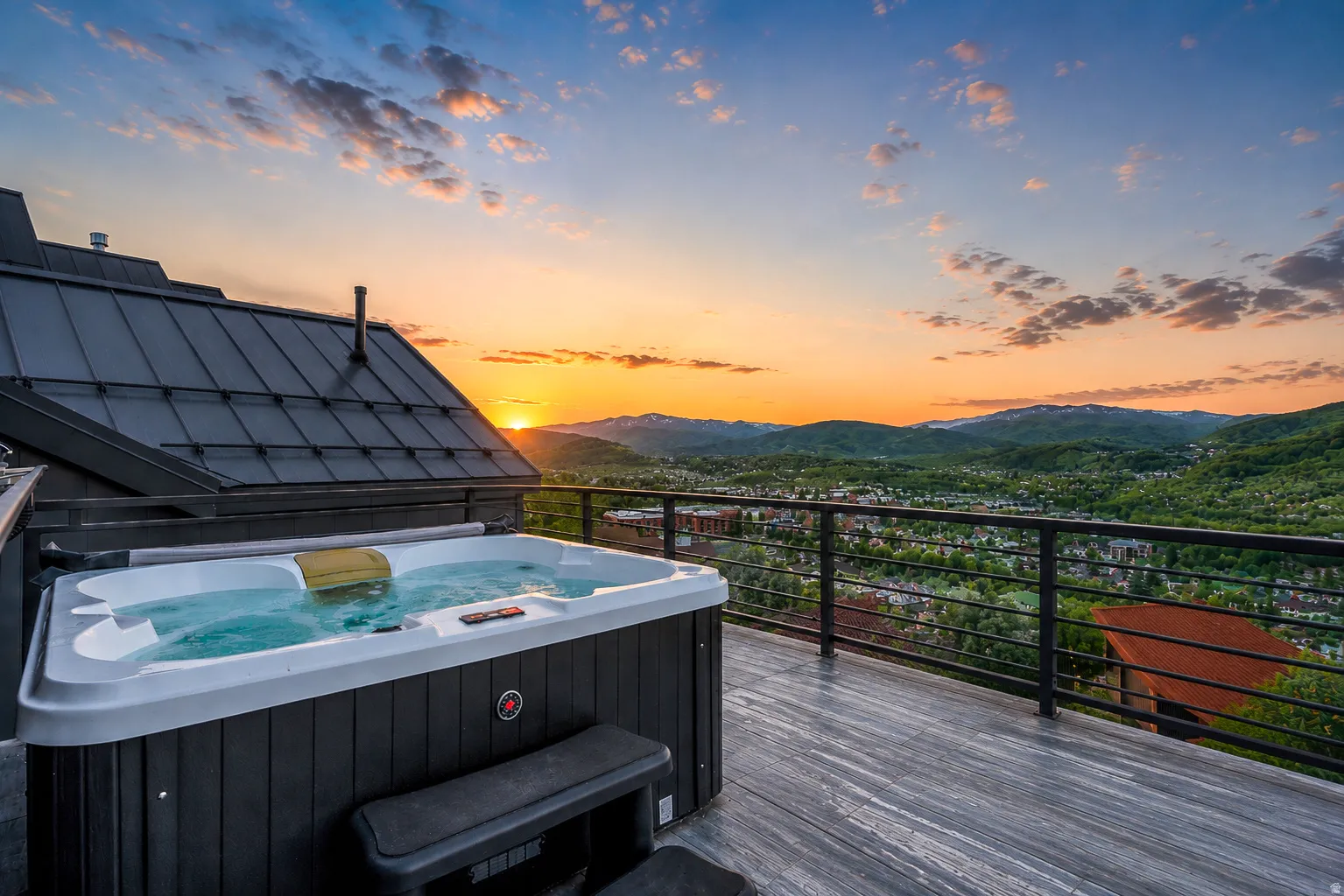 Expansive outdoor deck featuring a hot tub, cable railing system, and grey wood-finish flooring