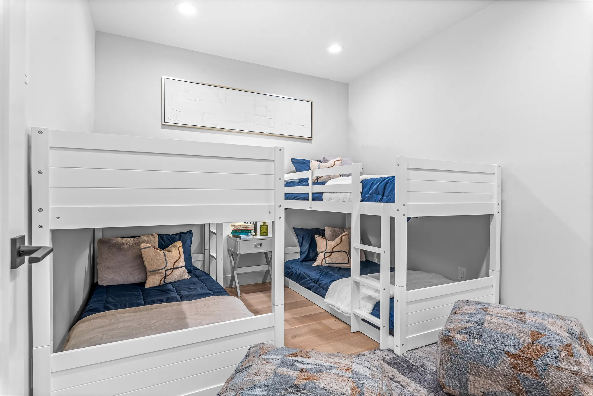 Bright bedroom featuring multiple built-in bunk beds, recessed lighting, and light wood-finish flooring