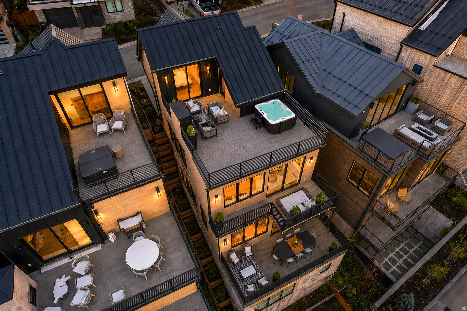 Modern multi-level dwelling with dark metal roofing and multiple outdoor living spaces