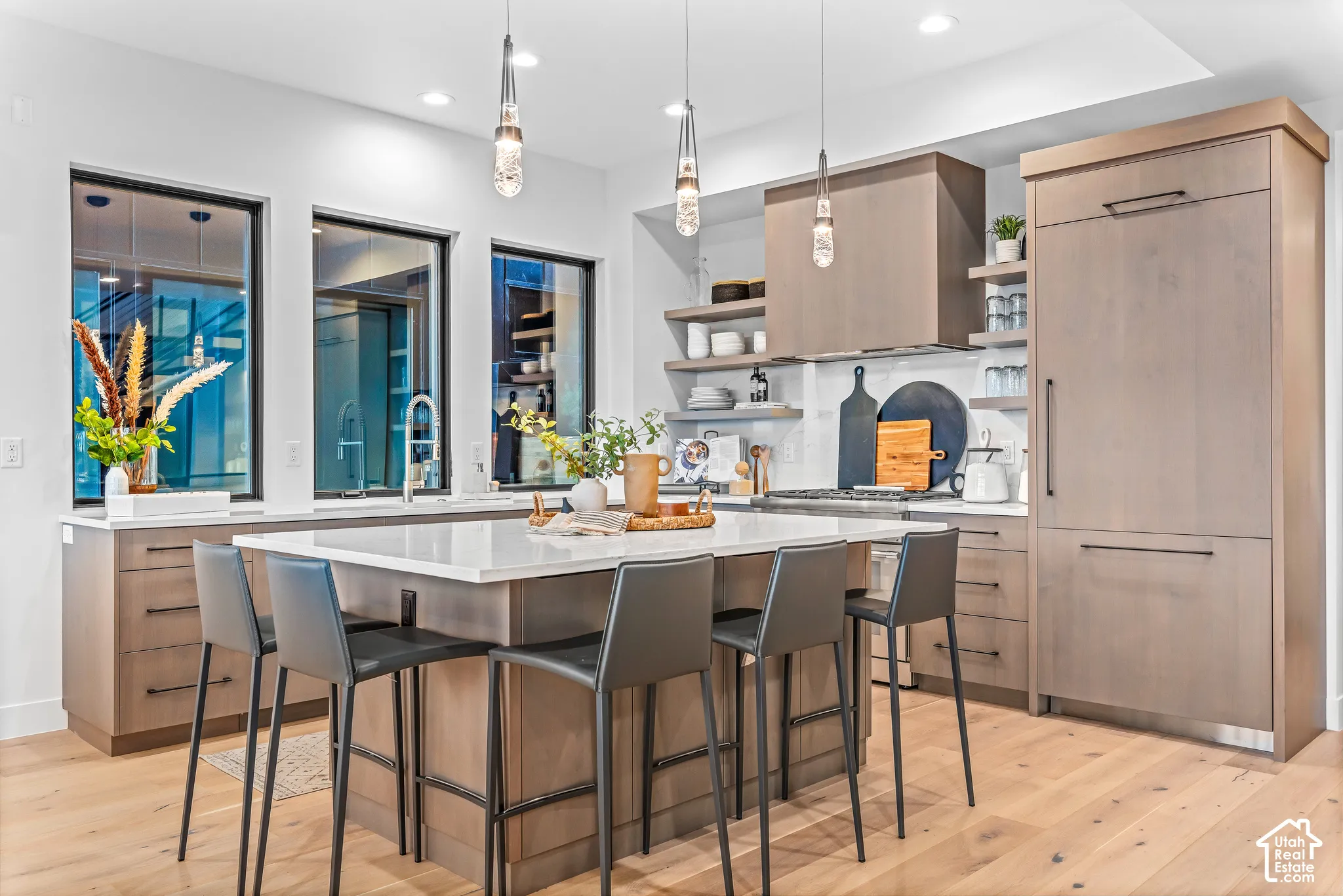 Kitchen featuring a large central island with seating, integrated appliances, wood-finish cabinetry, and extensive counter space