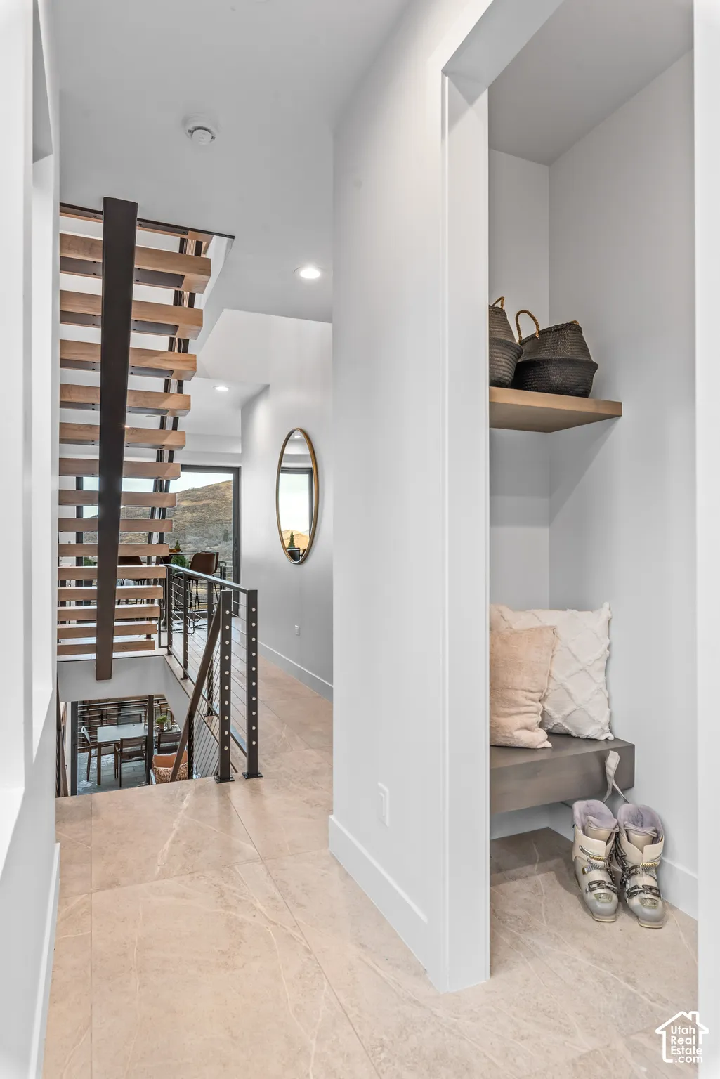 Hallway featuring large format tile flooring, a built-in bench with a floating shelf, and a modern open-tread staircase with metal railings