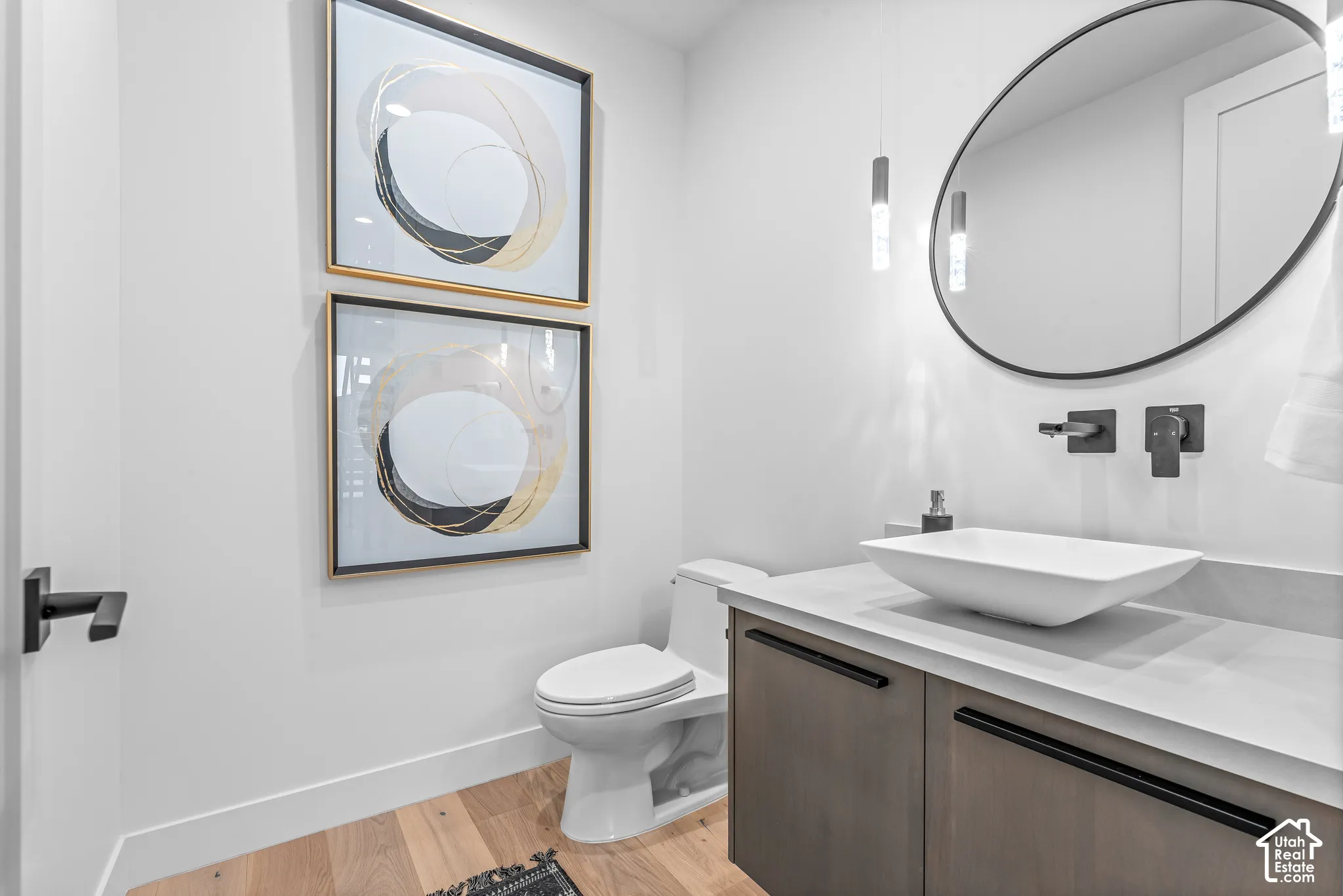 Contemporary powder room featuring a floating vanity with a vessel sink, wall-mounted matte black faucet, and a round black-framed mirror