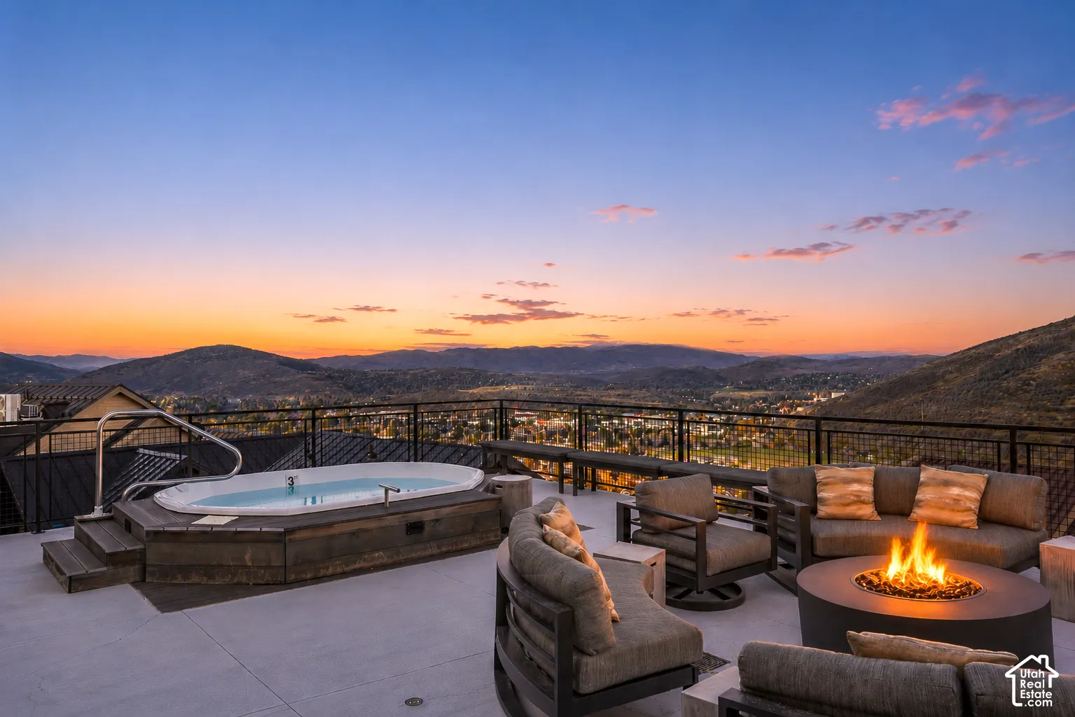 Expansive outdoor patio featuring a built-in hot tub with steps, a gas fire pit, and metal railings