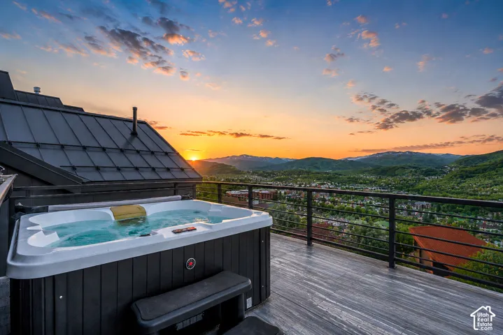 Expansive outdoor deck featuring a hot tub, cable railing system, and grey wood-finish flooring