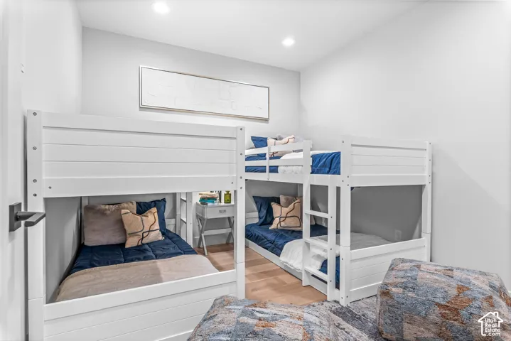 Bright bedroom featuring multiple built-in bunk beds, recessed lighting, and light wood-finish flooring