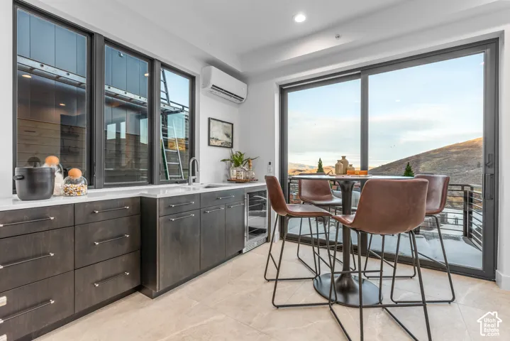 Wet bar featuring dark wood-finish cabinetry, a white countertop, a built-in beverage refrigerator, and a stainless steel sink with a gooseneck faucet
