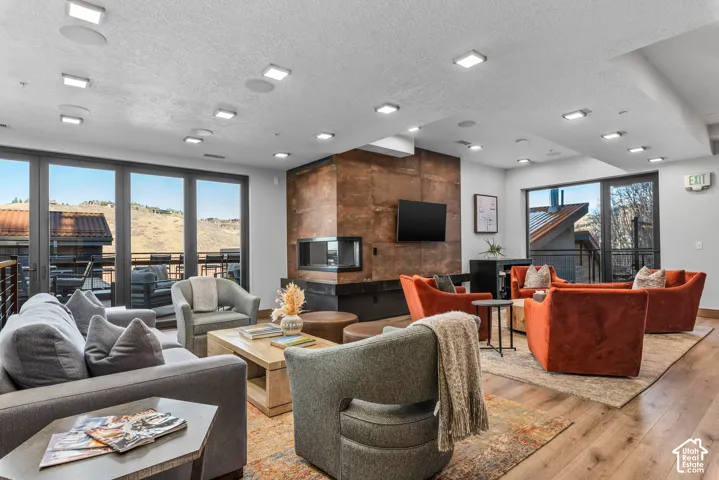 Spacious common area featuring a modern fireplace with a distressed metal surround, wood-finish flooring, and ample recessed lighting