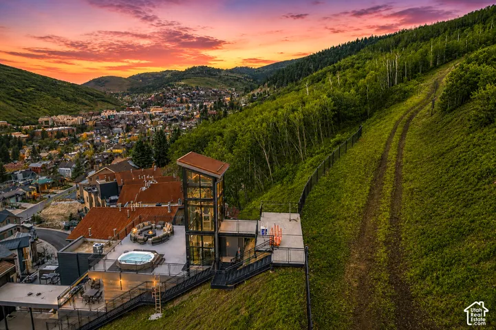 Multi-level outdoor deck featuring a hot tub, a fire pit, and a glass-enclosed structure