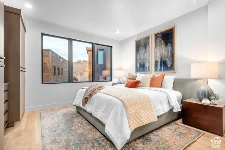 Bedroom featuring light wood-finish flooring and a large window with black framing