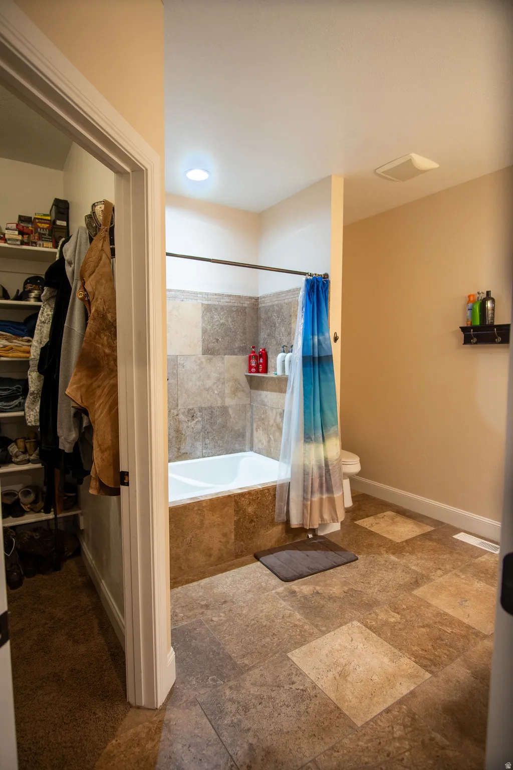Bathroom featuring a tiled bathtub surround, white tub, and a toilet