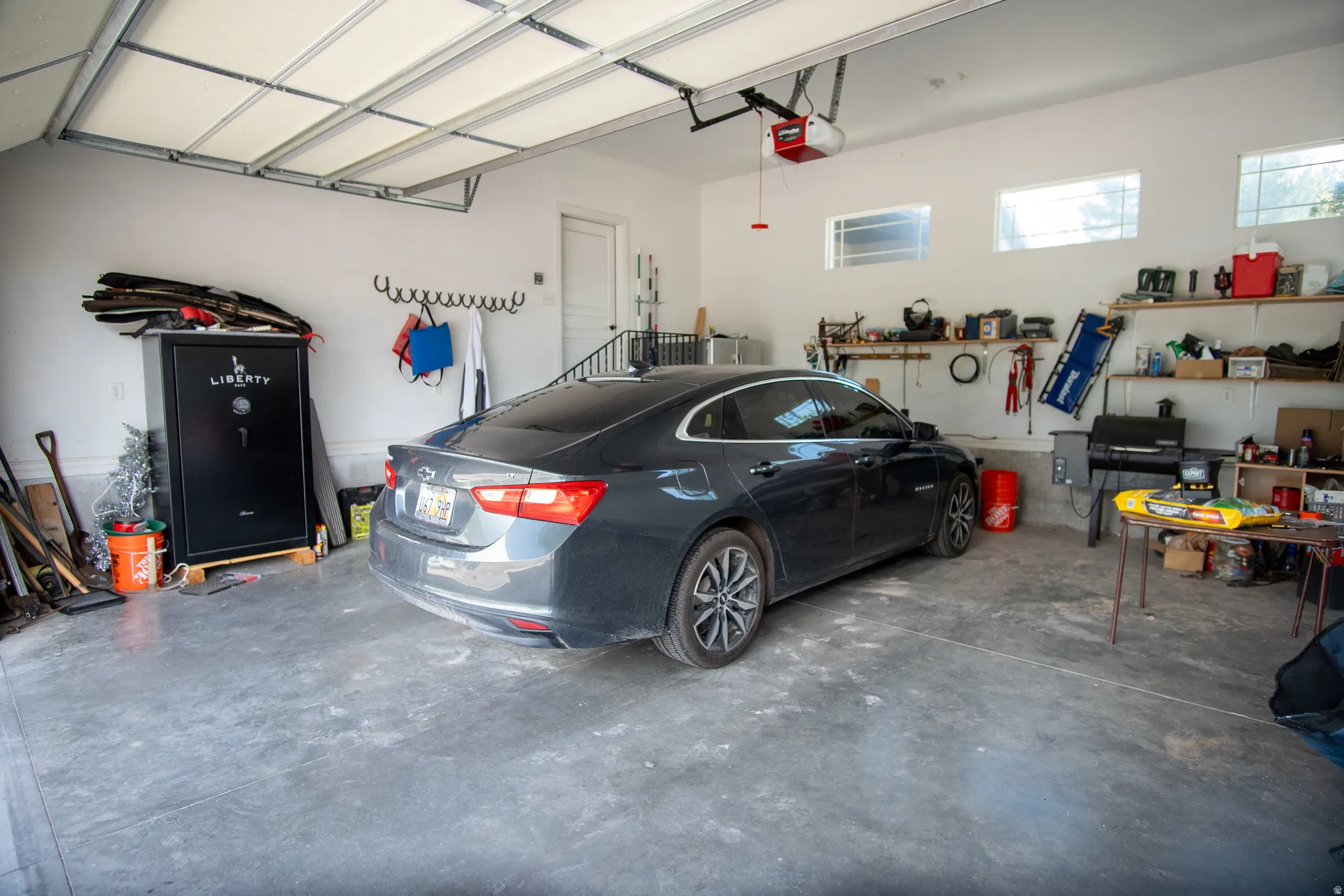Attached garage with concrete flooring, automatic garage door opener, and multiple wall-mounted windows providing natural light