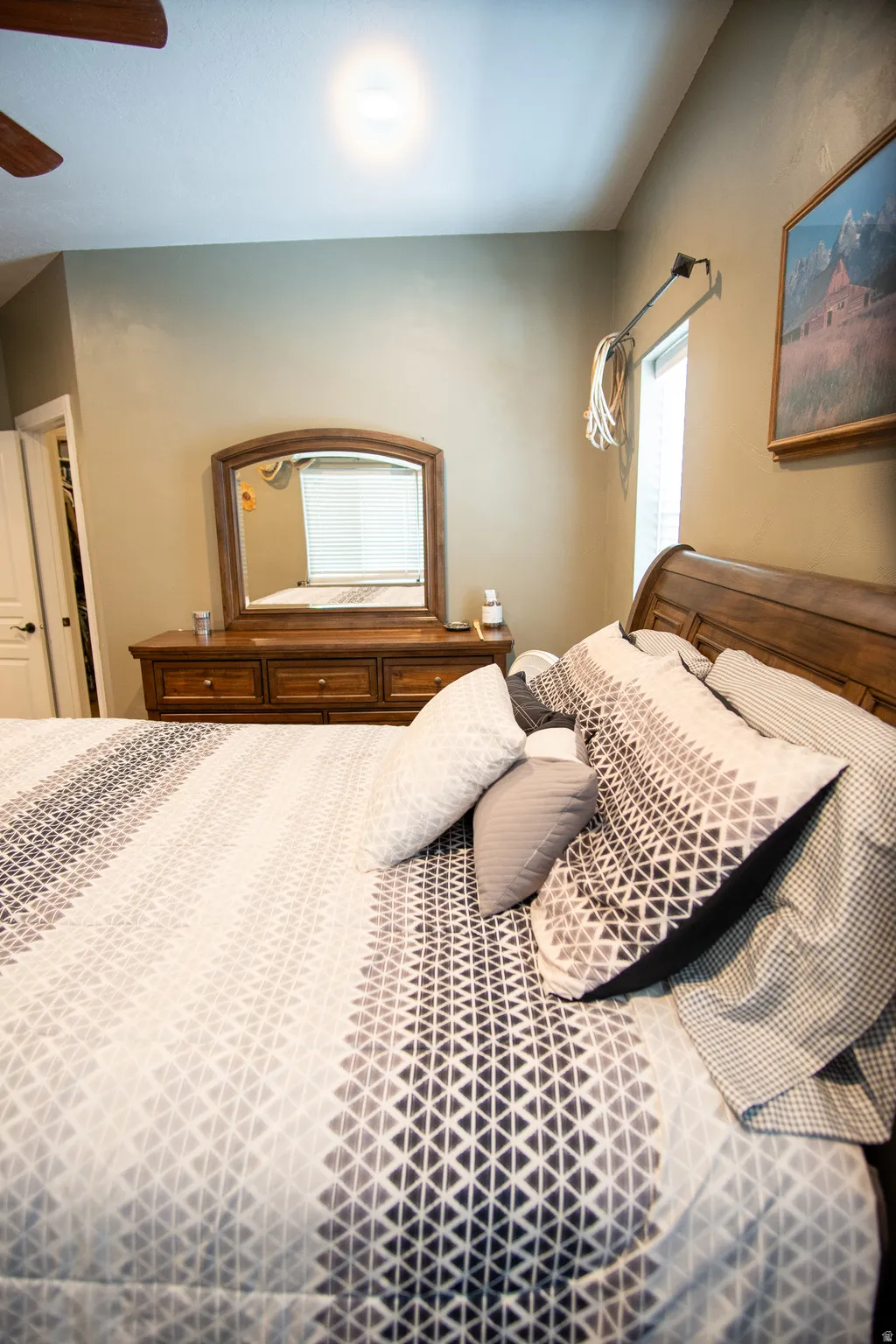 Bedroom featuring wood-finish bed frame, coordinated dresser with mirror, ceiling fan, and recessed lighting