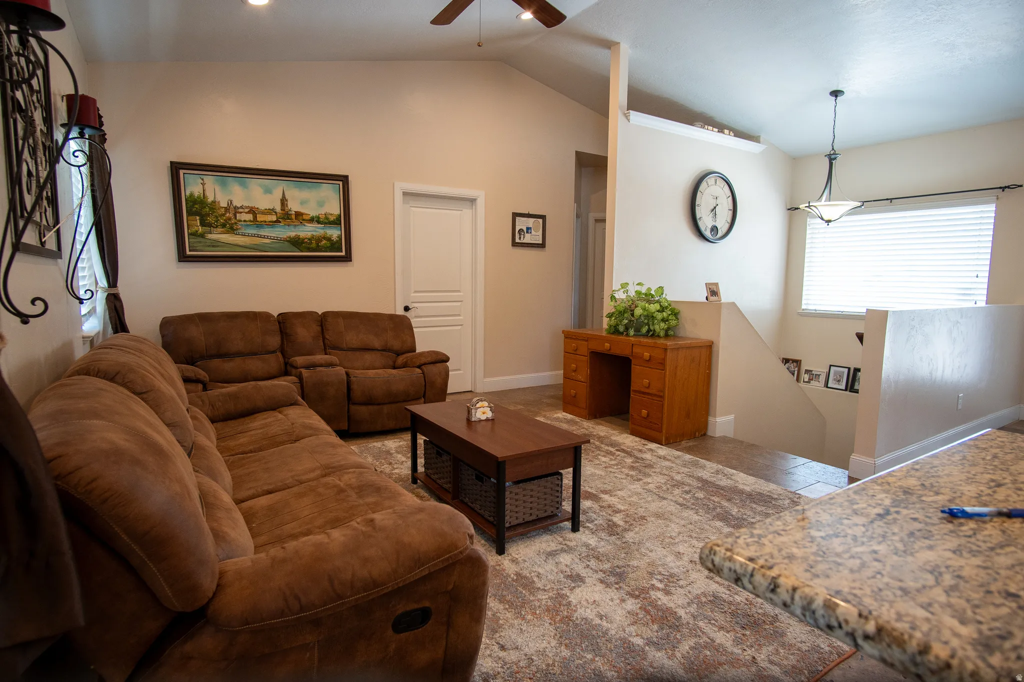 Vaulted ceilings accent this living space, featuring a ceiling fan with integrated lighting