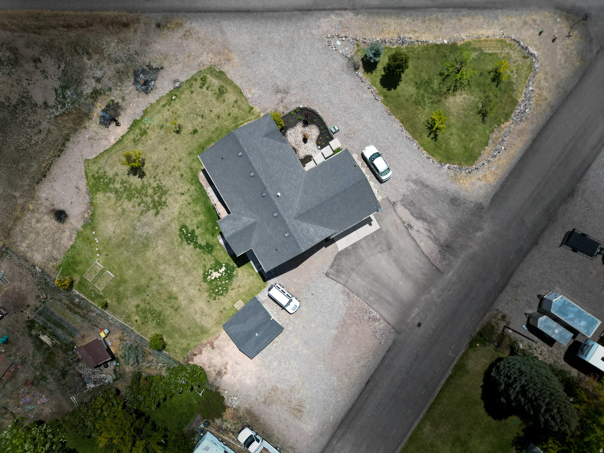 Single-story residence featuring a dark shingle roof and a light-colored driveway