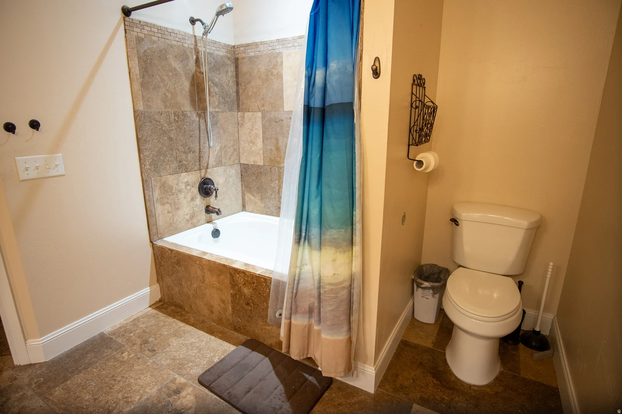 Bathtub and shower combination with full-height tile surround, dark bronze fixtures, and a coordinating tile tub skirt