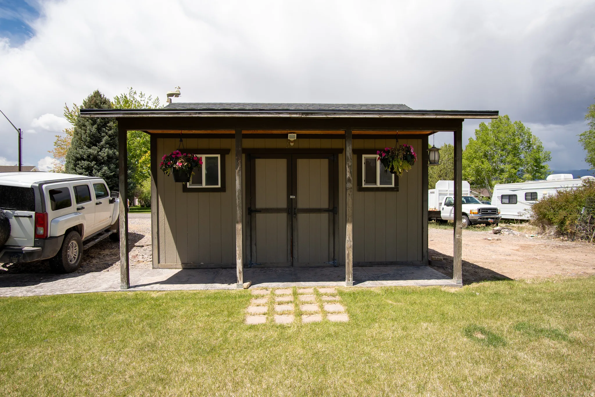 Freestanding structure featuring a covered front porch with exposed wood posts, a shingle roof, and a panel siding exterior