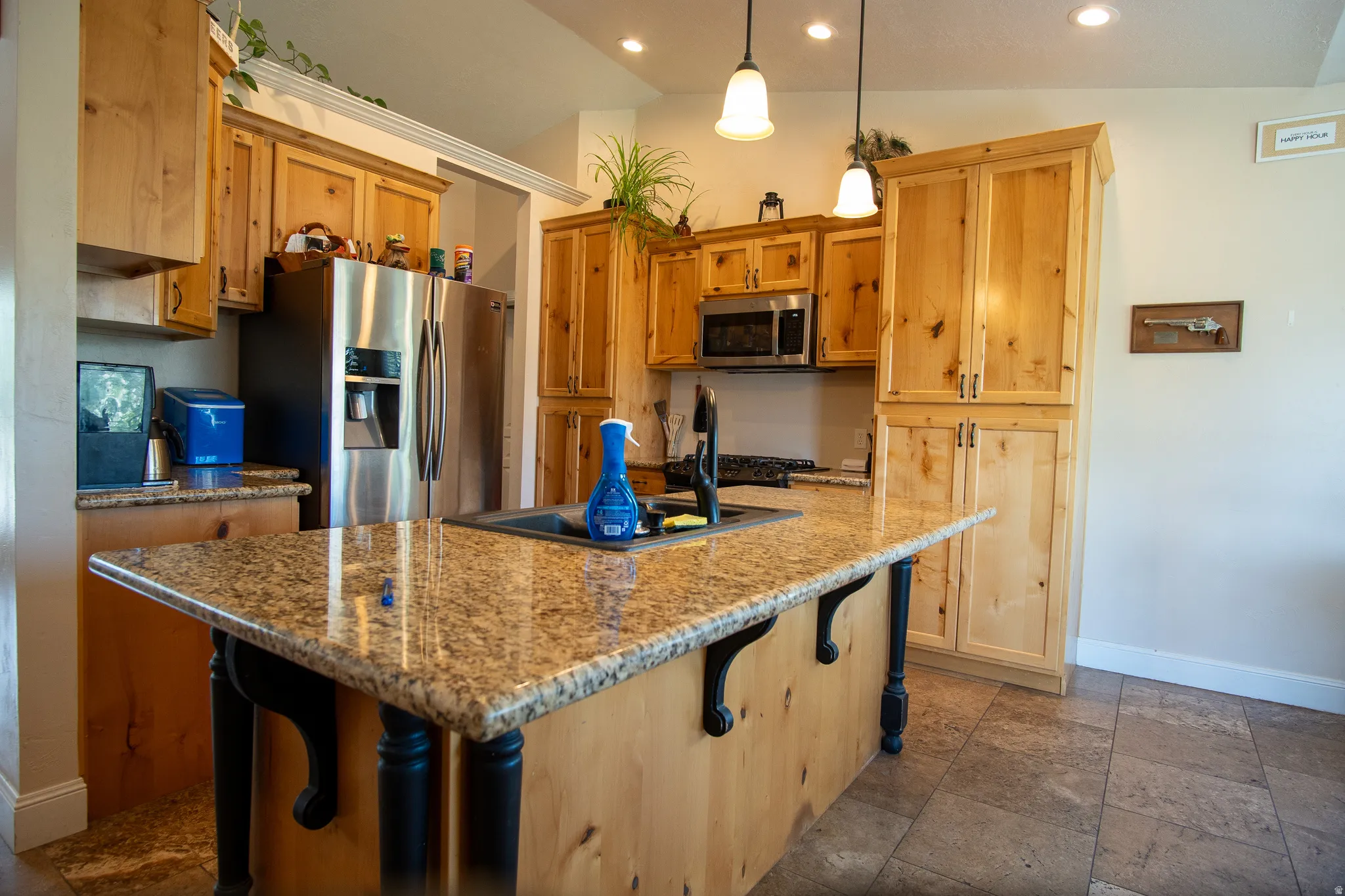 Kitchen featuring light wood cabinetry, granite countertops, a center island with sink, stainless steel appliances, and tiled flooring
