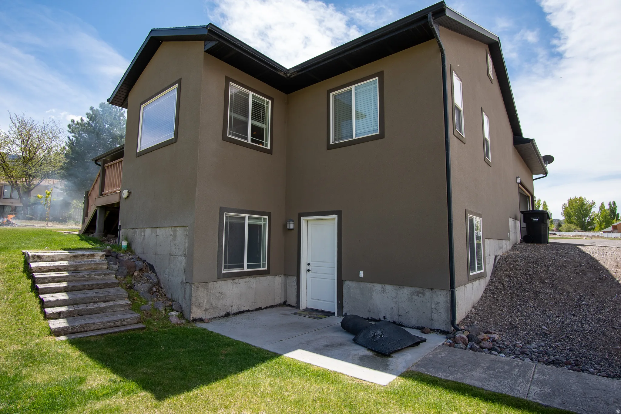 Exterior stucco finish with white trim windows and a concrete patio