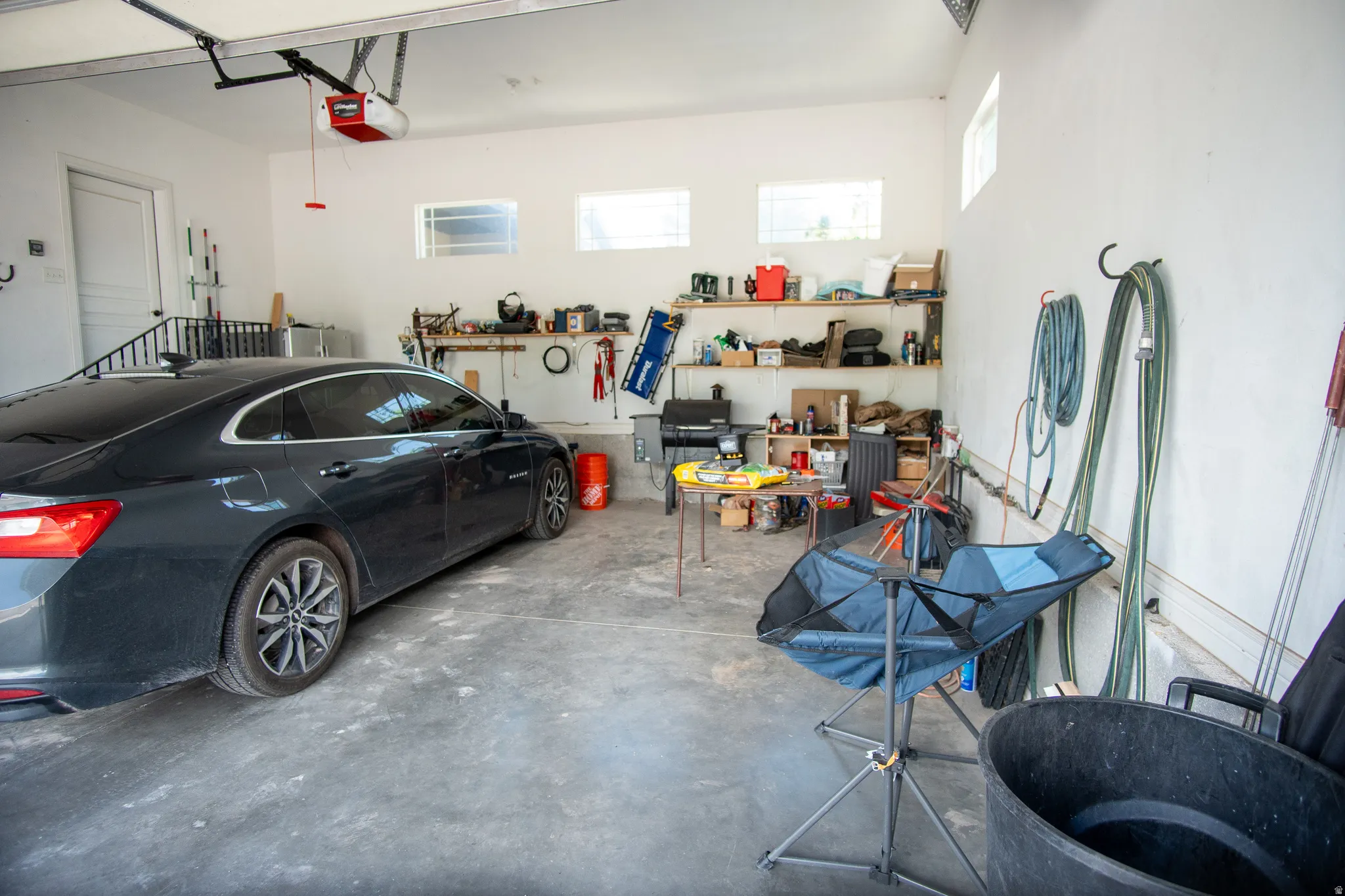Spacious two-car garage featuring a concrete floor, white painted walls, and built-in shelving for organized storage