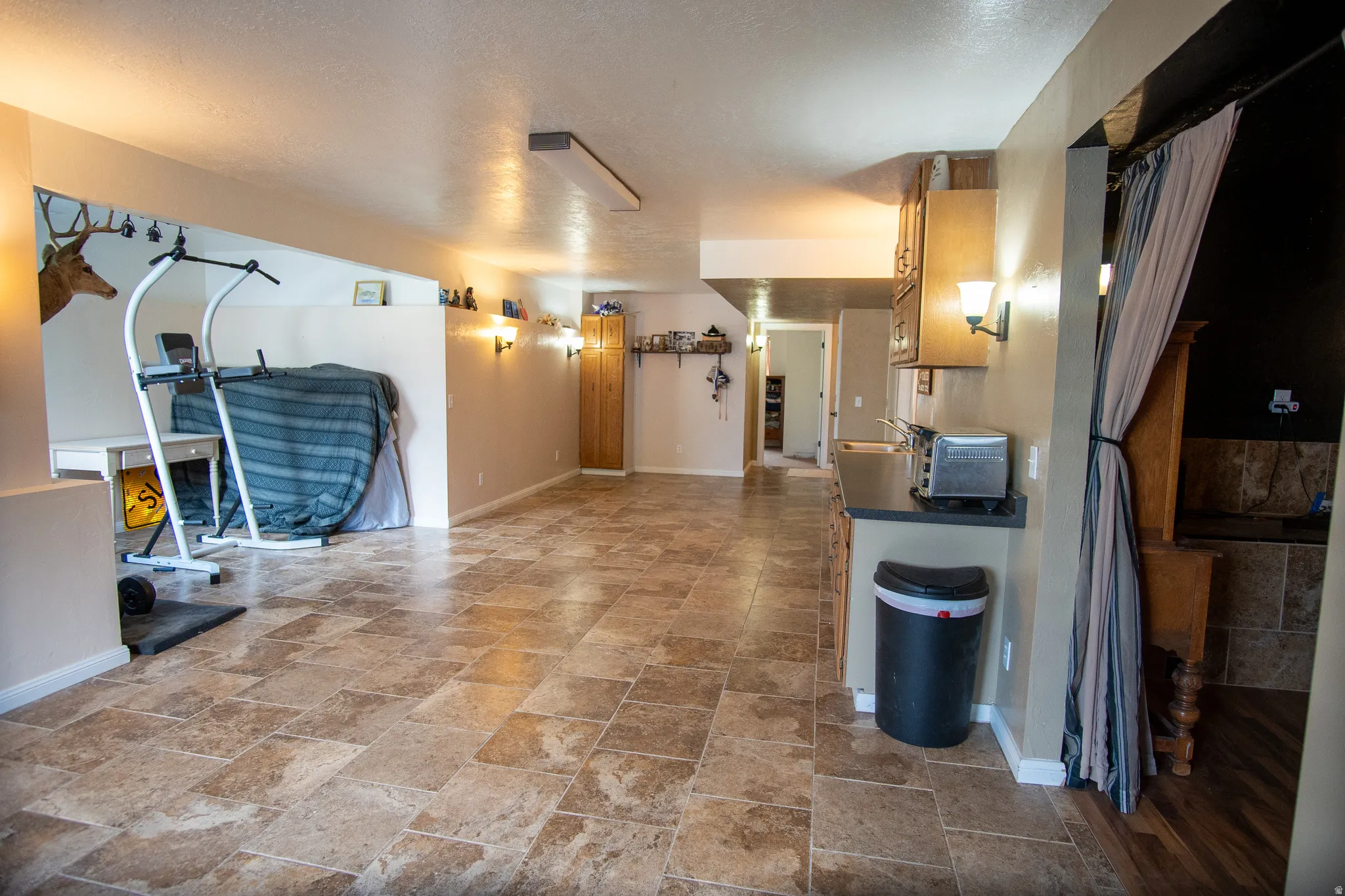 Spacious open-concept room featuring square tile flooring, recessed lighting, and wall sconces