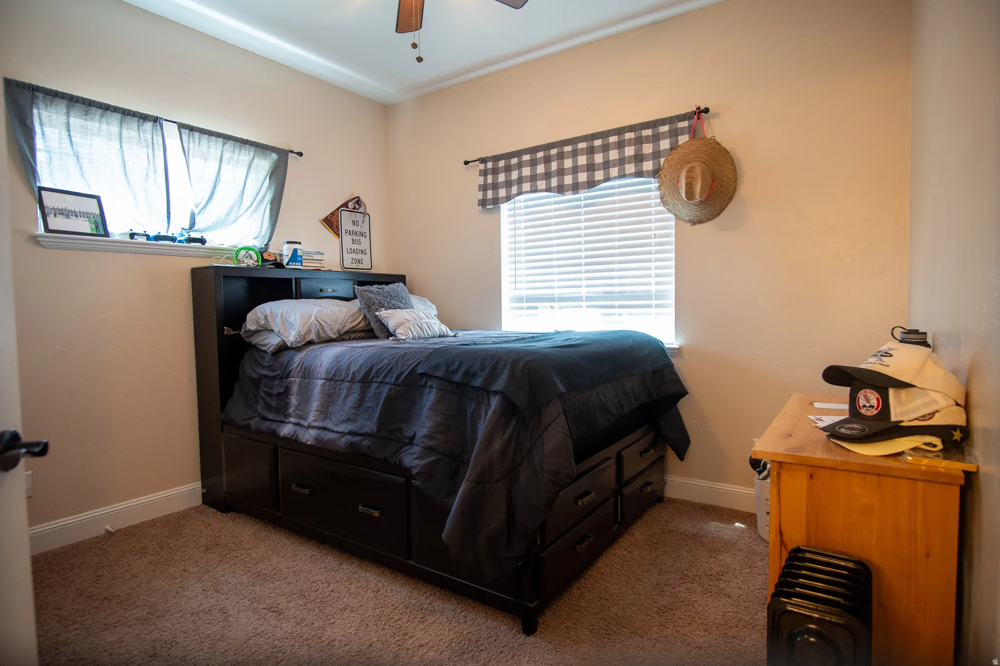 Carpeted bedroom featuring two windows with blinds, a ceiling fan, and light-toned wall paint