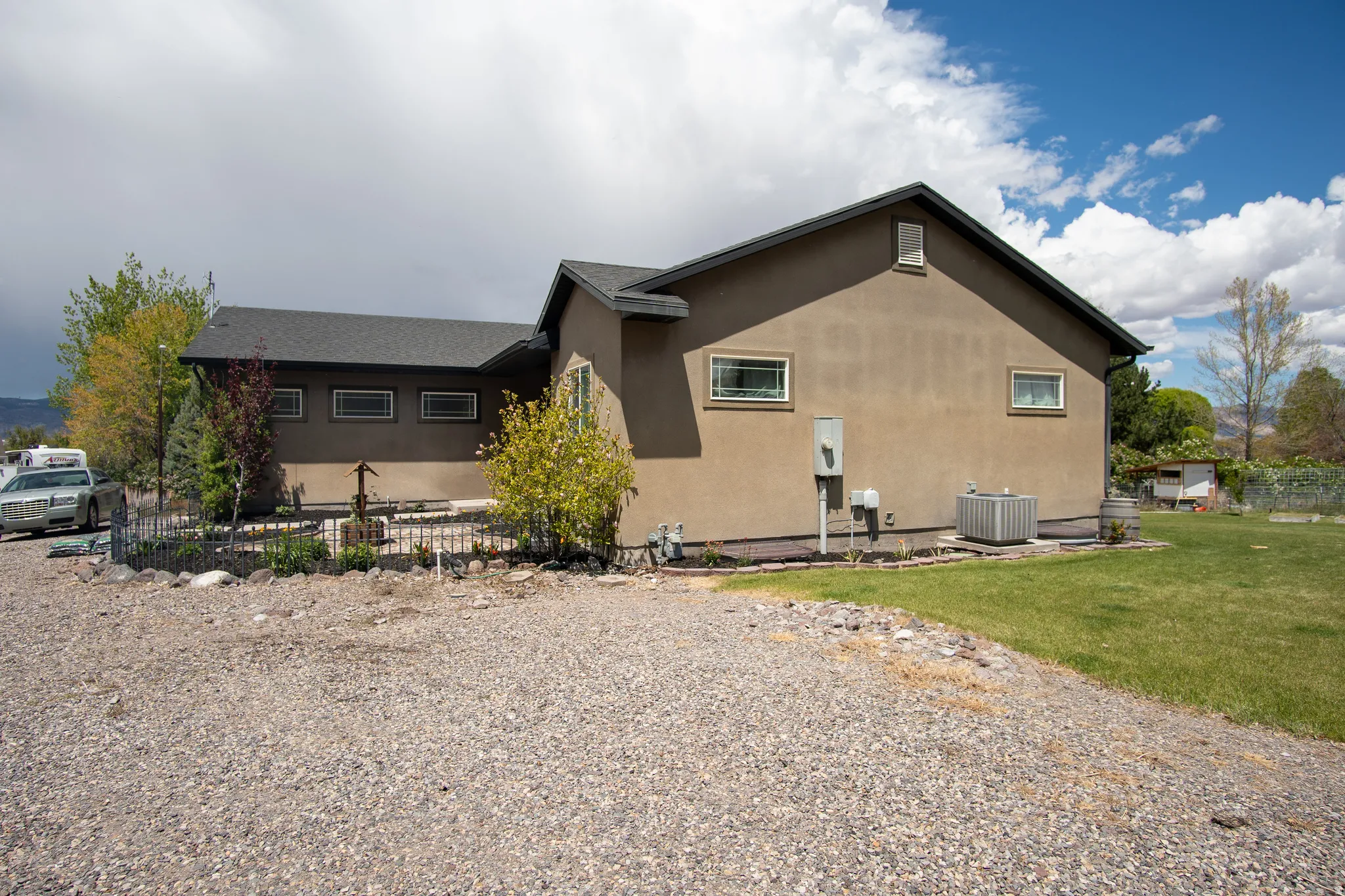 Stucco exterior with a dark shingle roof, featuring multiple windows with horizontal grilles