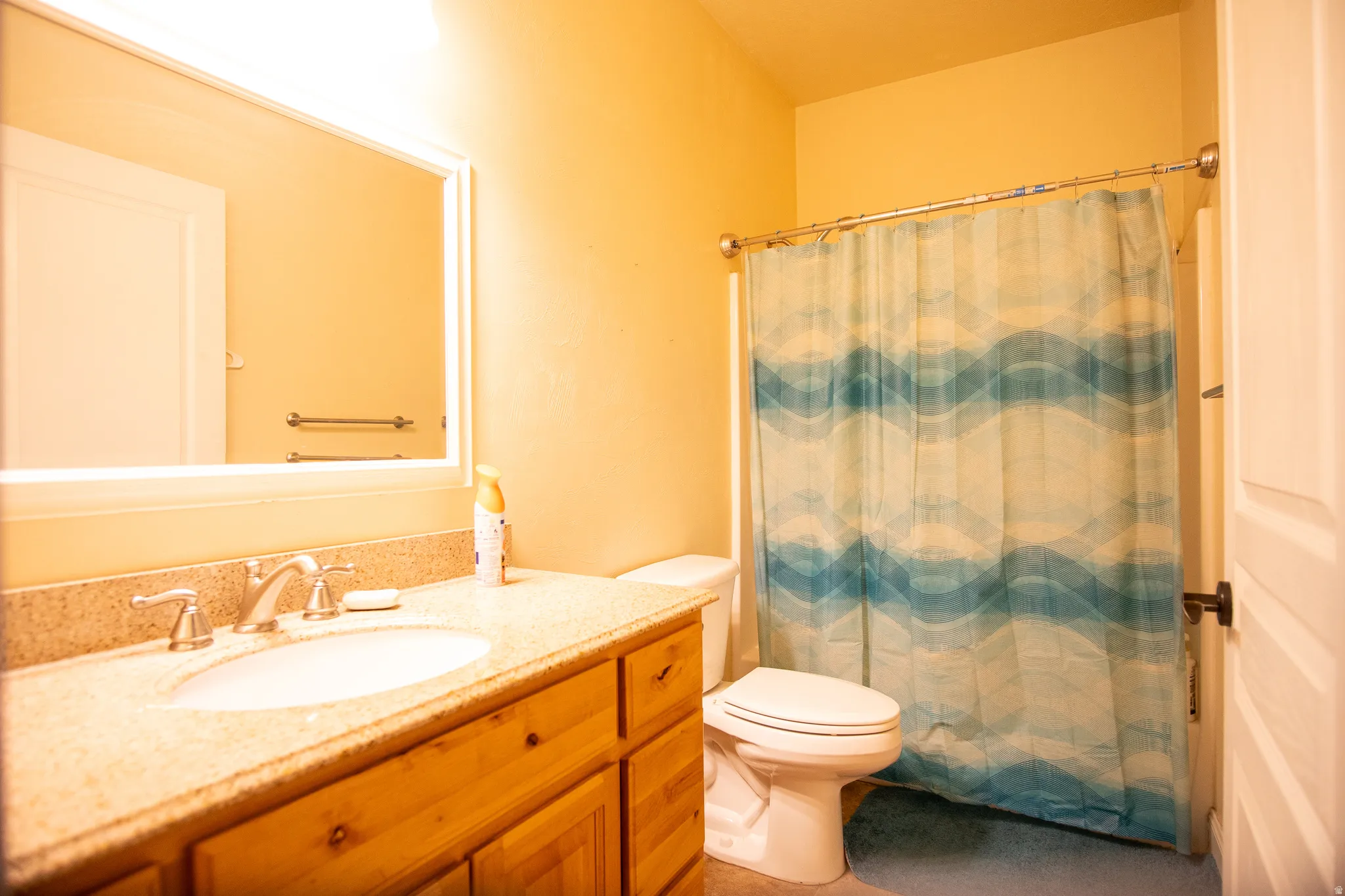Full bathroom featuring a single vanity with wood cabinetry and a speckled countertop