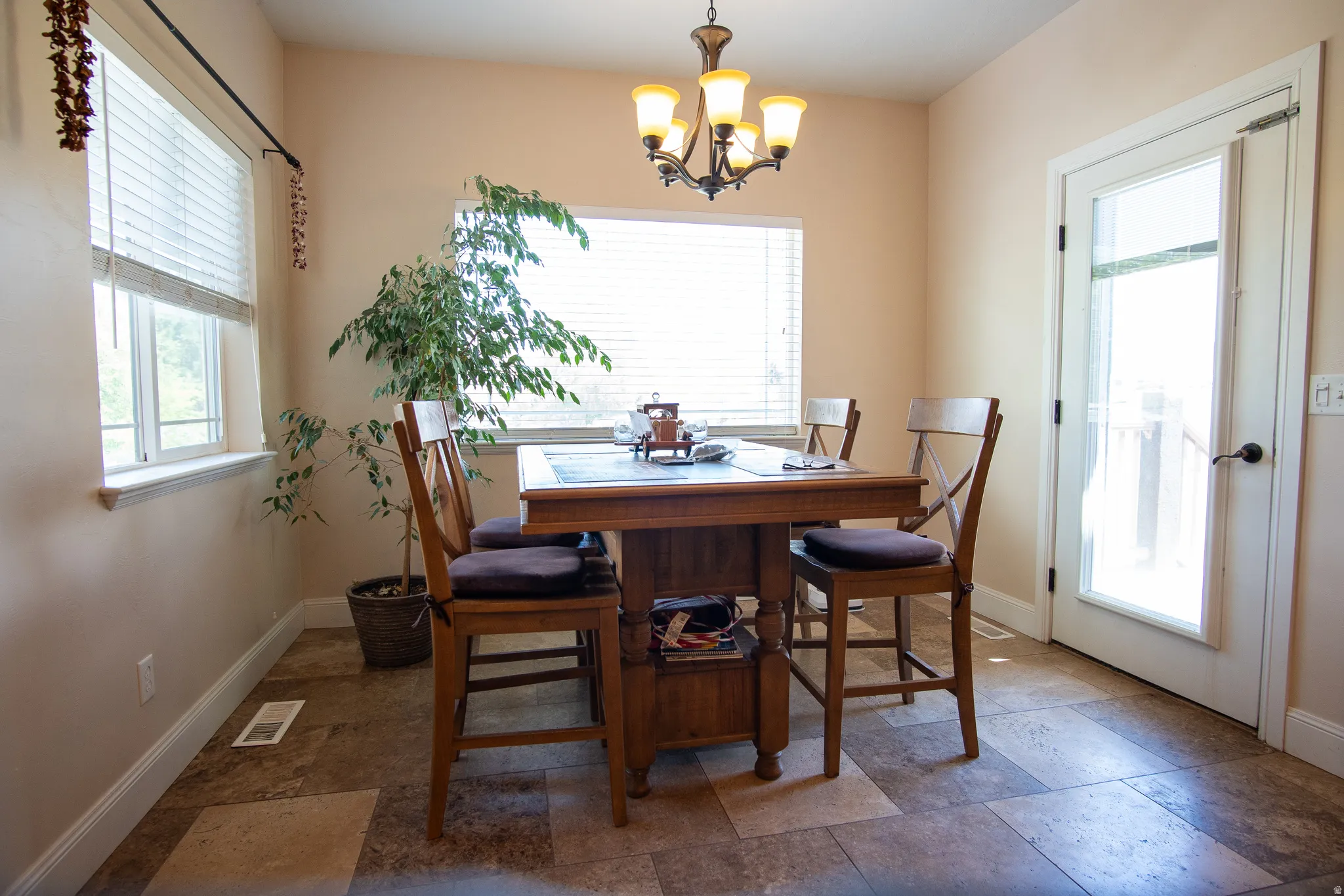 Dining area featuring multi-pane windows, a glass-panel door, and a bronze-finish chandelier
