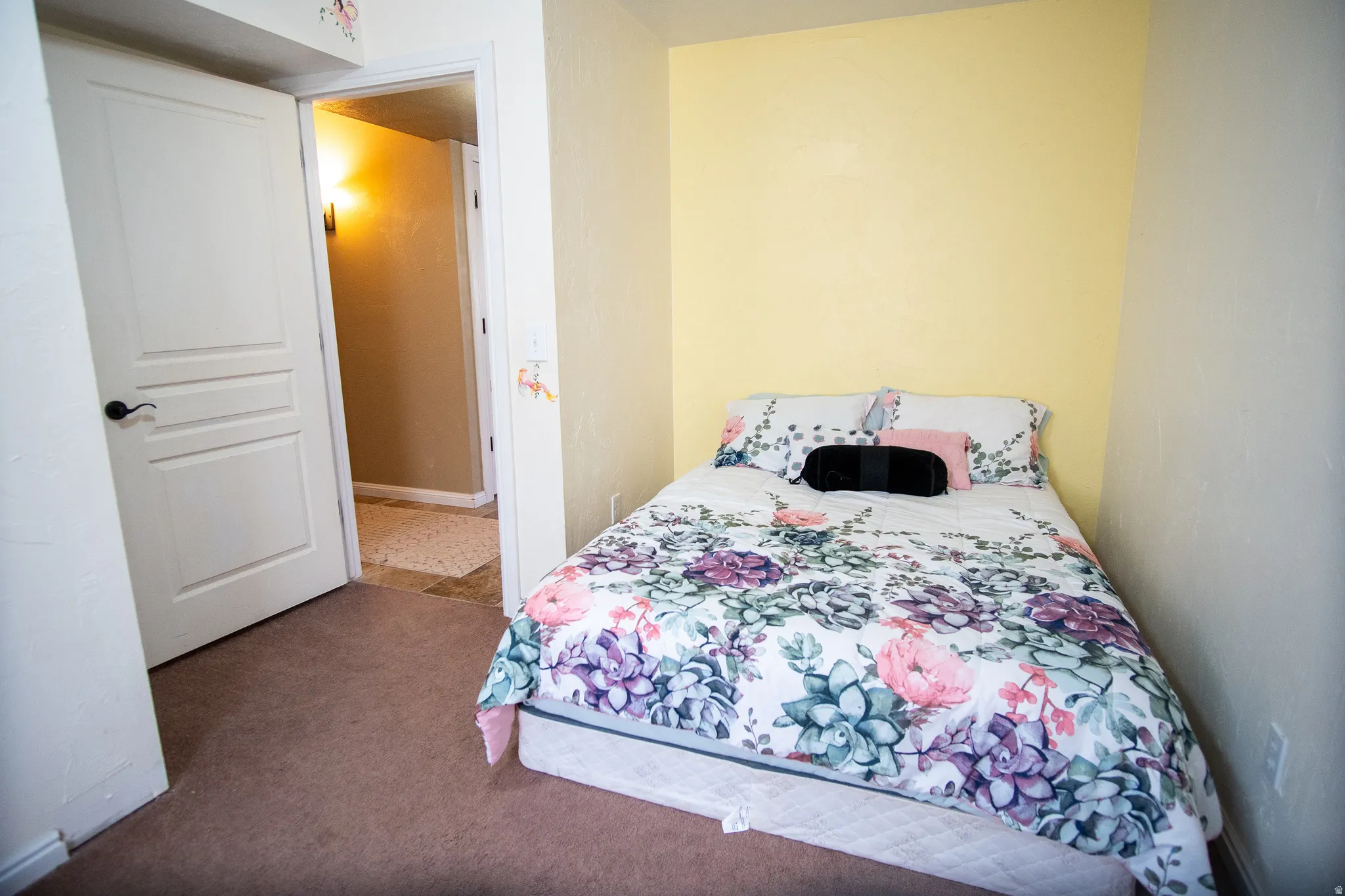 Bedroom featuring light yellow accent wall and neutral wall tones, complemented by brown carpet flooring