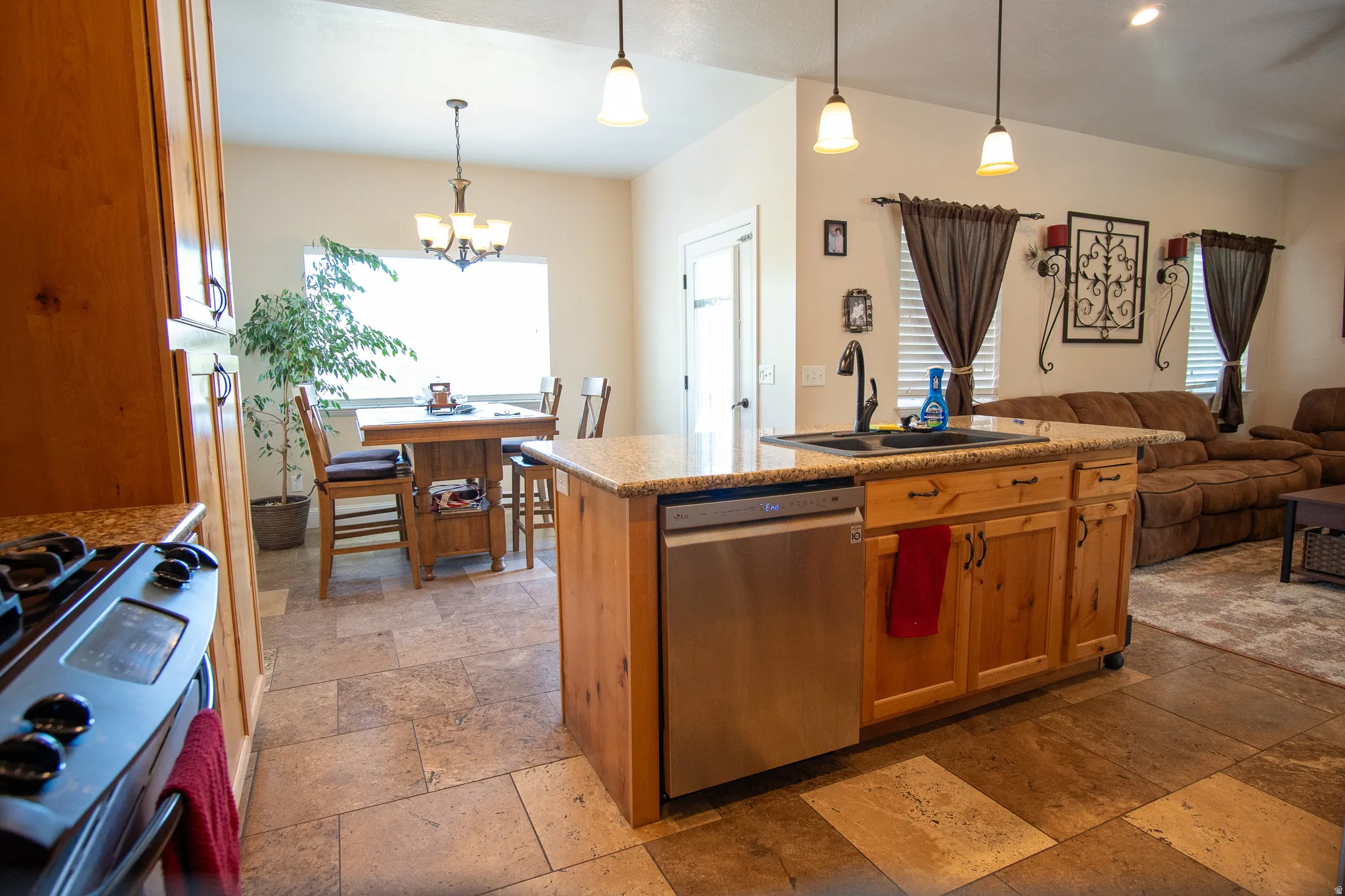 Kitchen featuring wood cabinetry, granite-style countertops, stainless steel dishwasher, and a black basin sink with a gooseneck faucet
