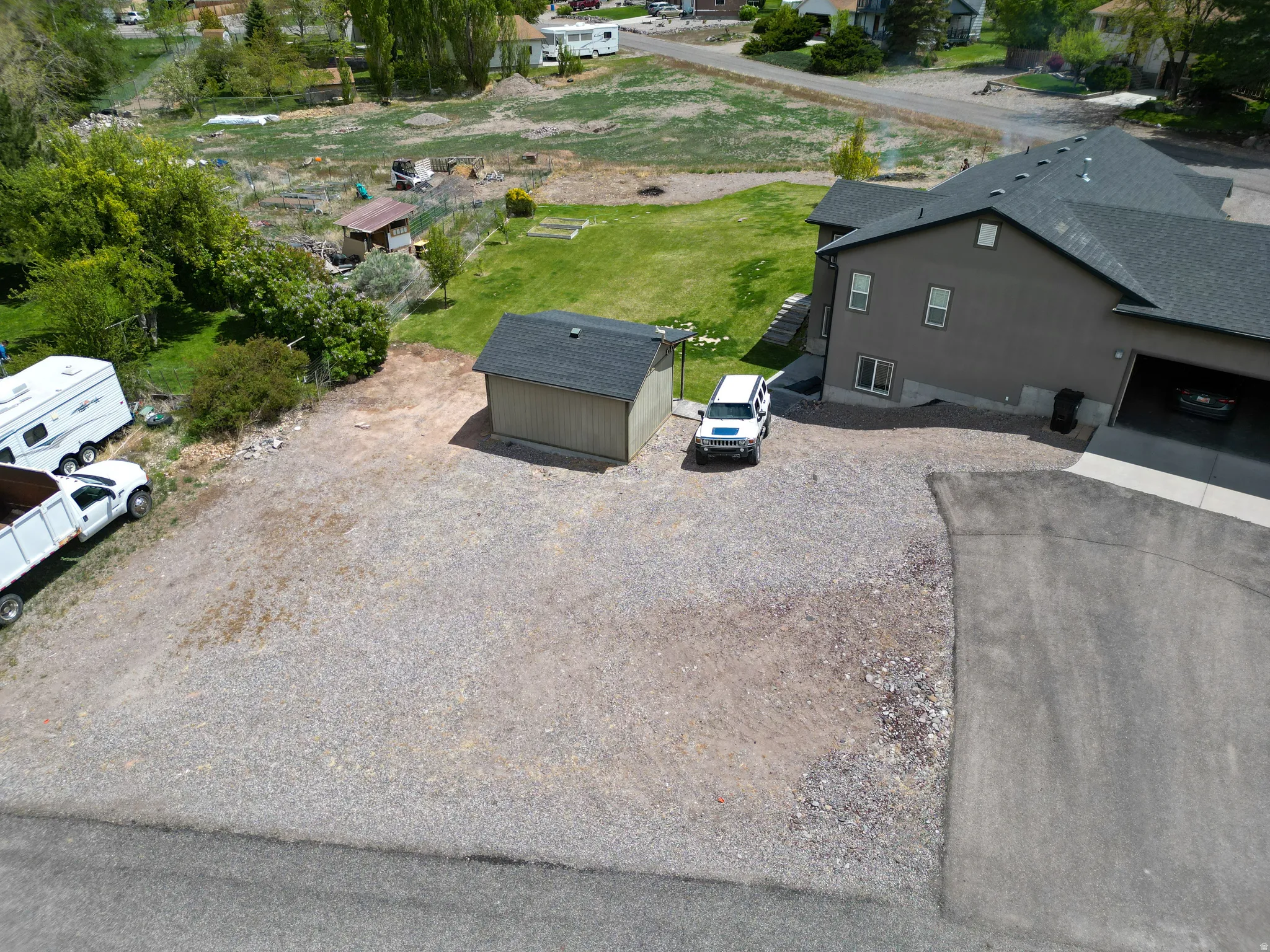 Two-story residence featuring a two-car garage, gravel driveway, and a separate shed with a dark roof