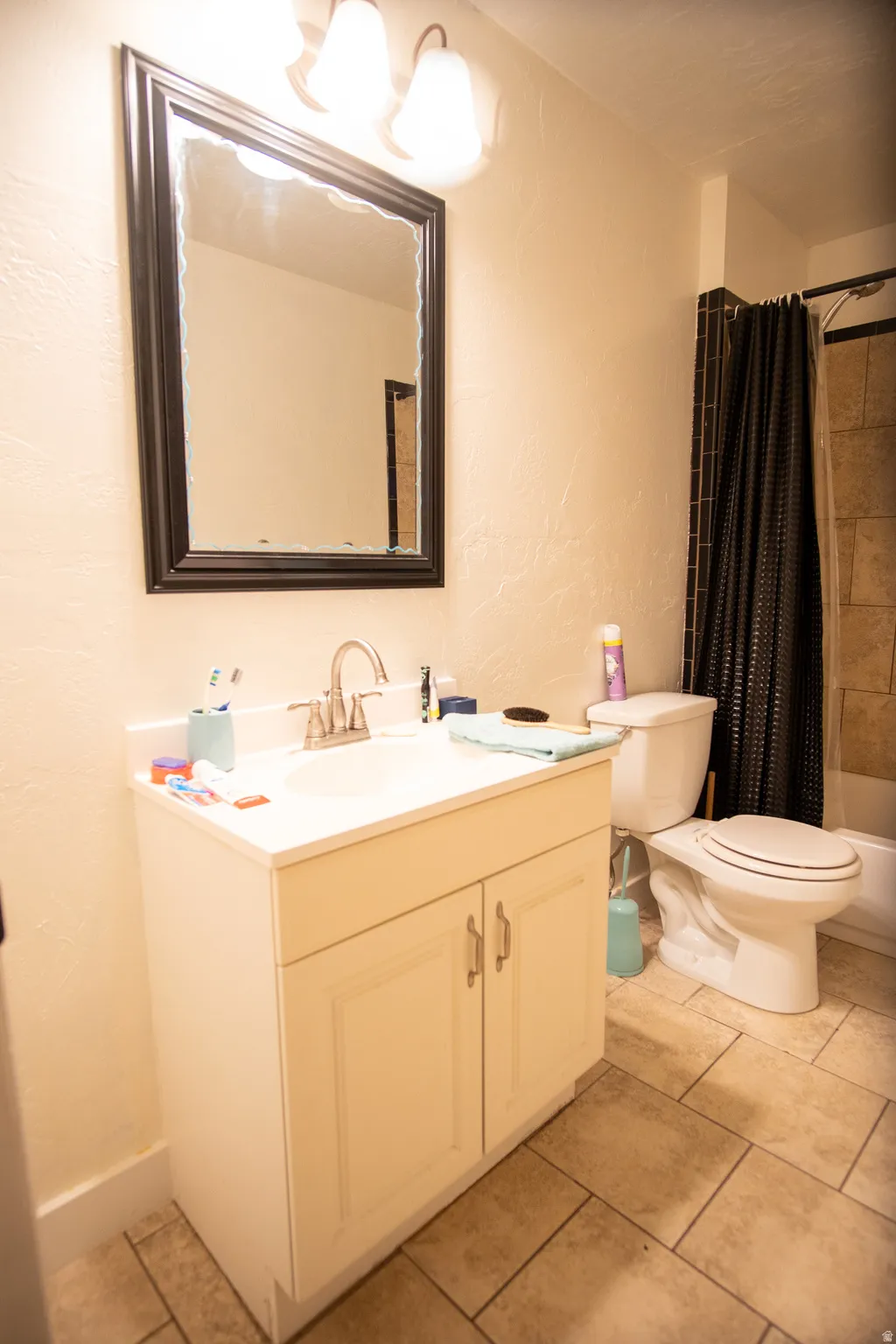 Bathroom featuring a single vanity with a white countertop, framed mirror, and two-light fixture