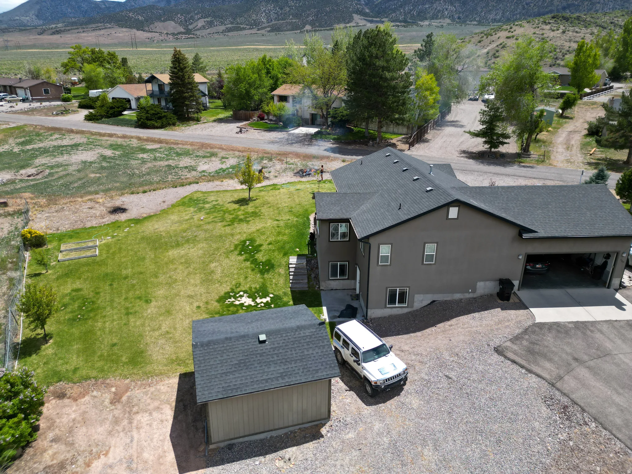 Contemporary residence featuring a dark gray exterior, a large attached garage, and a detached storage shed