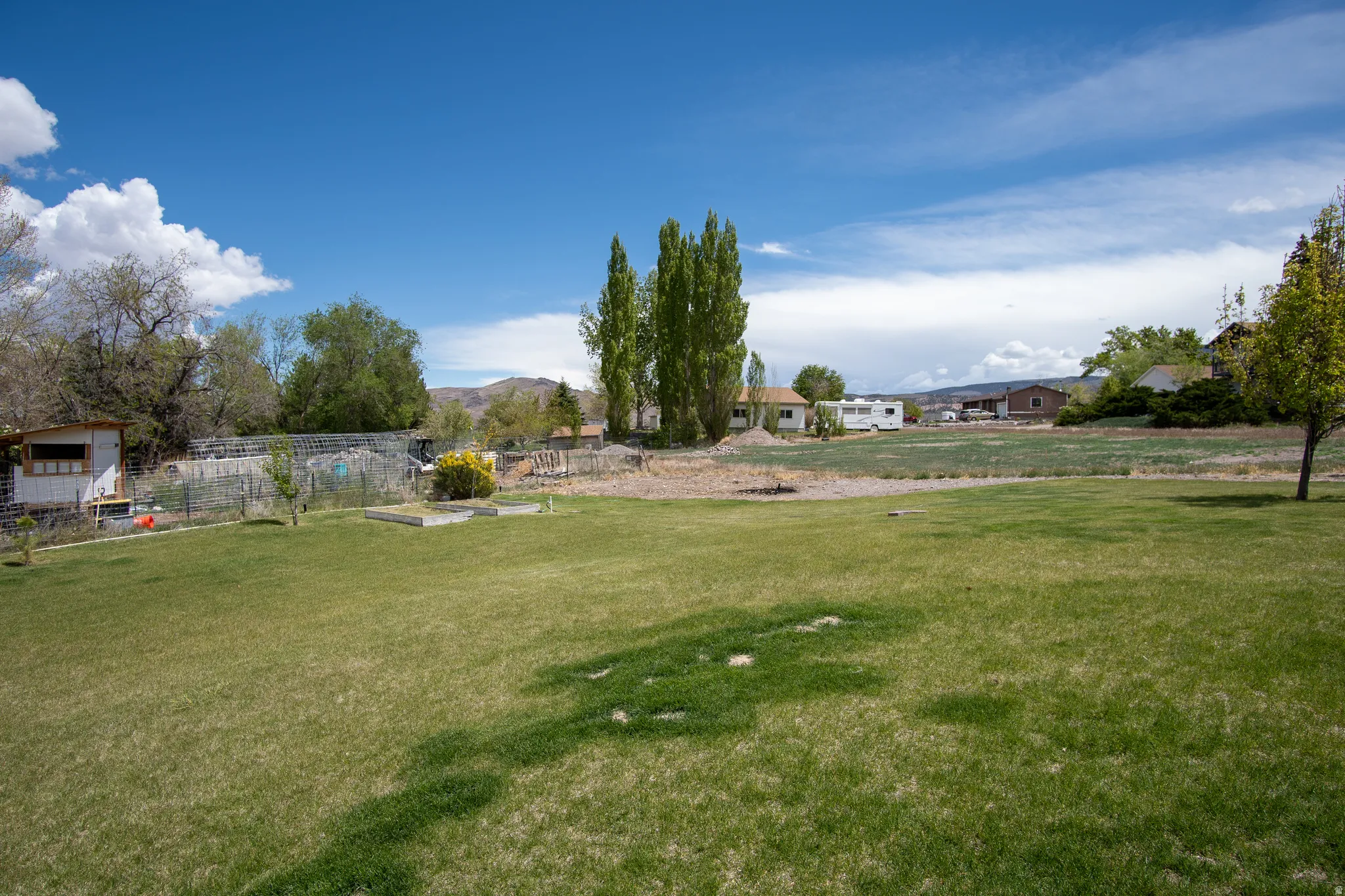 Expansive green lawn with established trees and raised garden beds