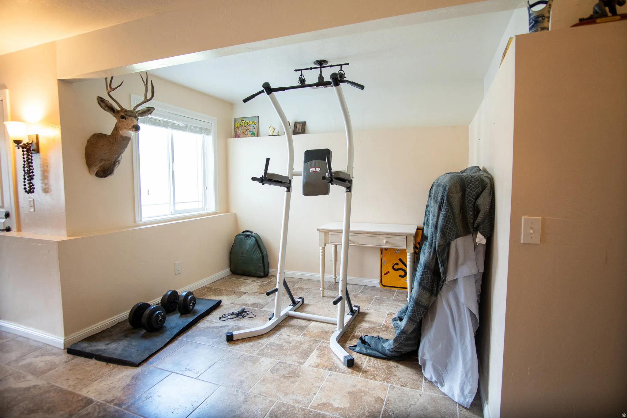 Lower-level area featuring recessed walls, a window, and durable tile flooring