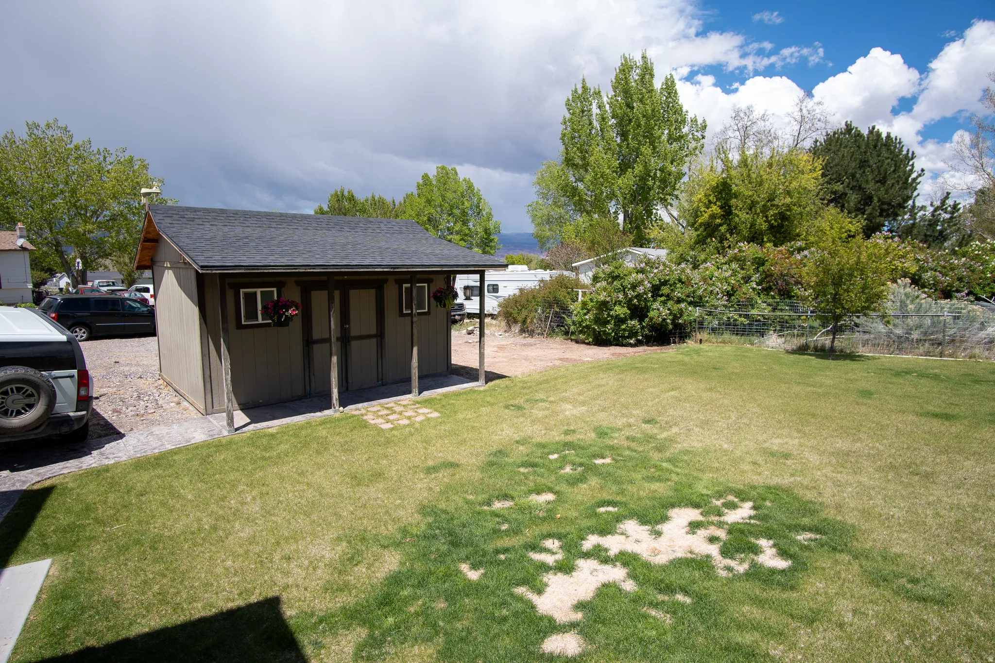 Detached storage shed with a shingled roof and covered porch