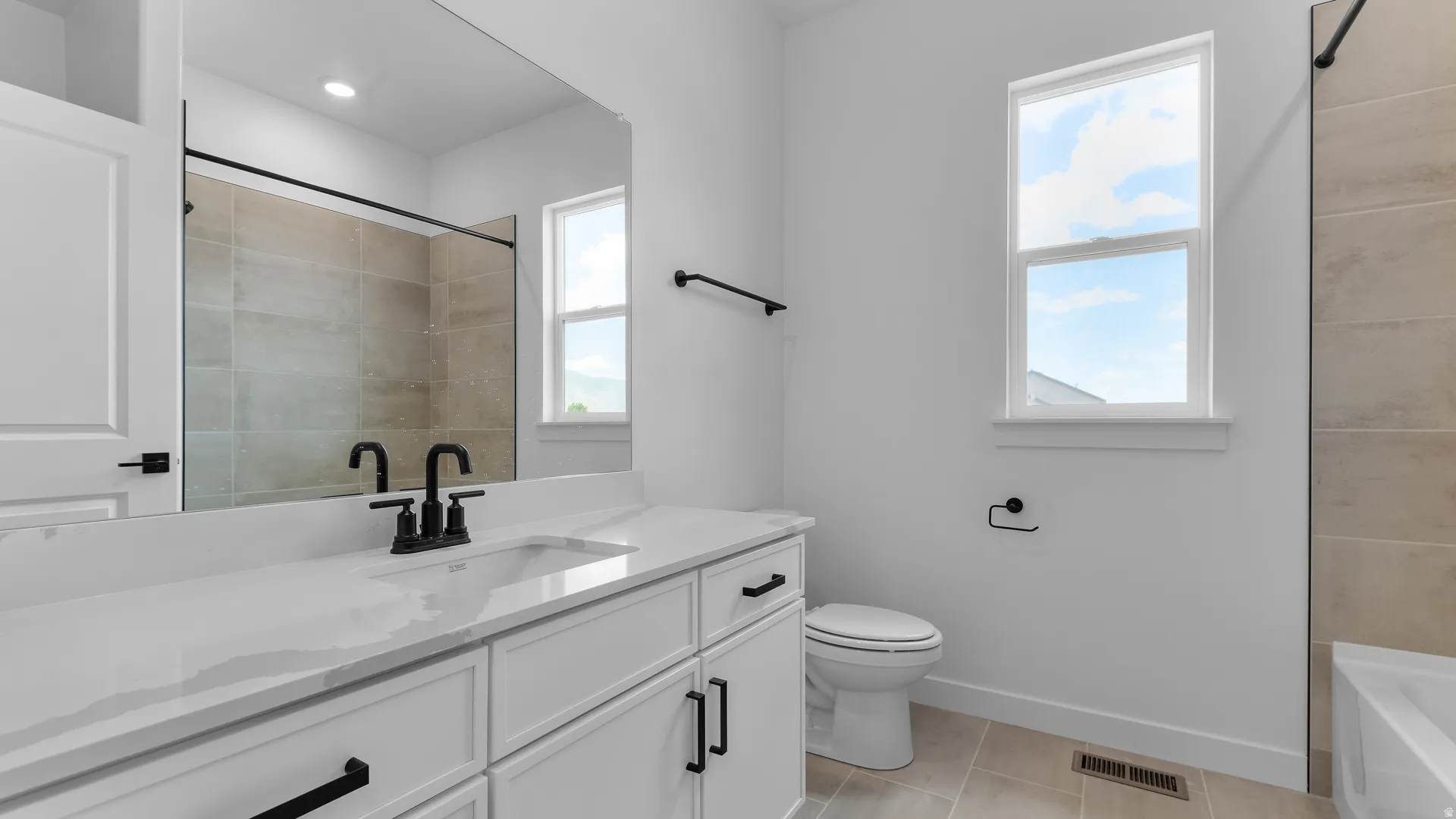 Contemporary bathroom featuring a white vanity with an integrated sink and matte black fixtures