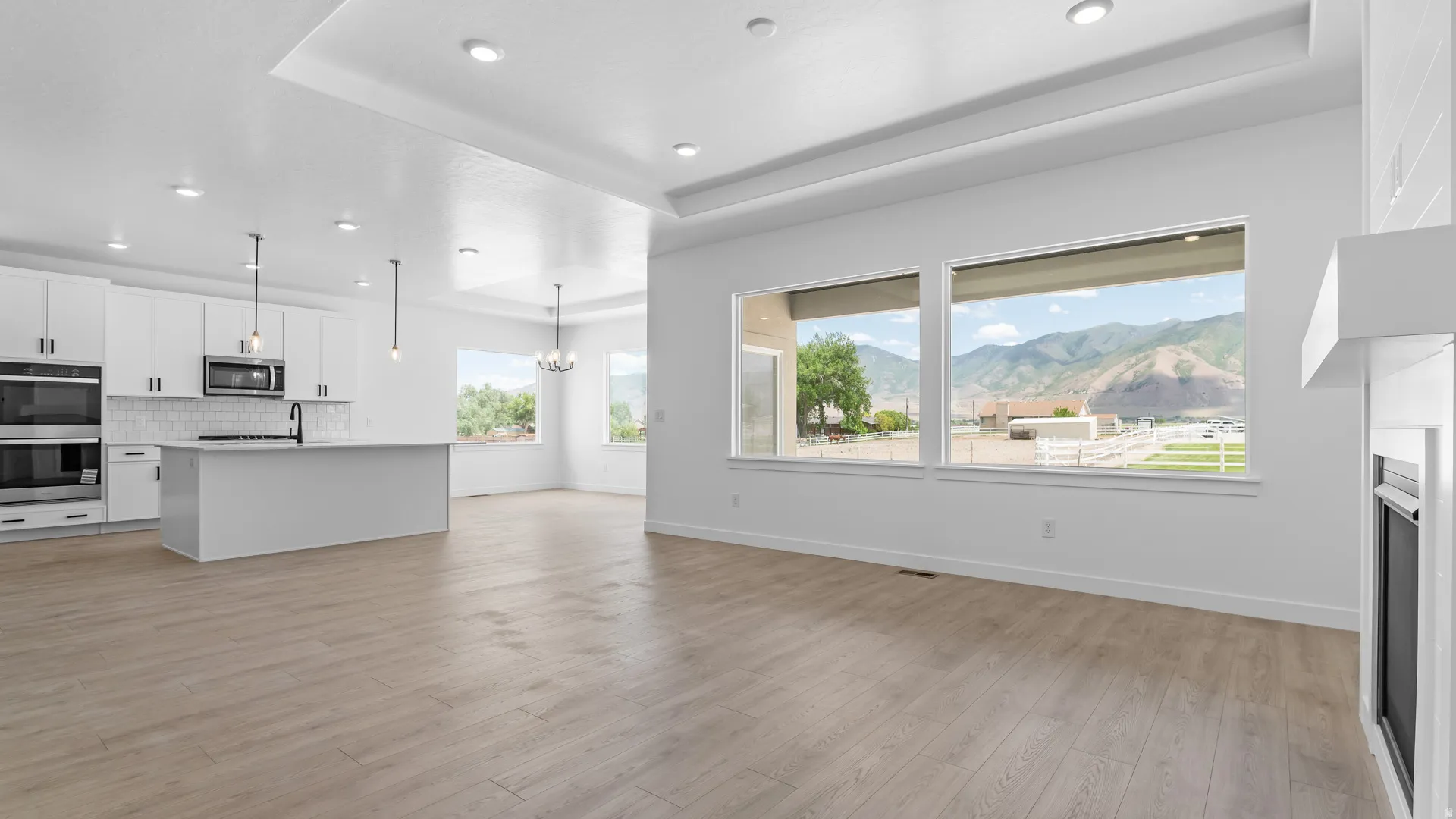 Open-concept living space featuring wood-finish flooring, recessed lighting, and large windows showcasing a mountain backdrop