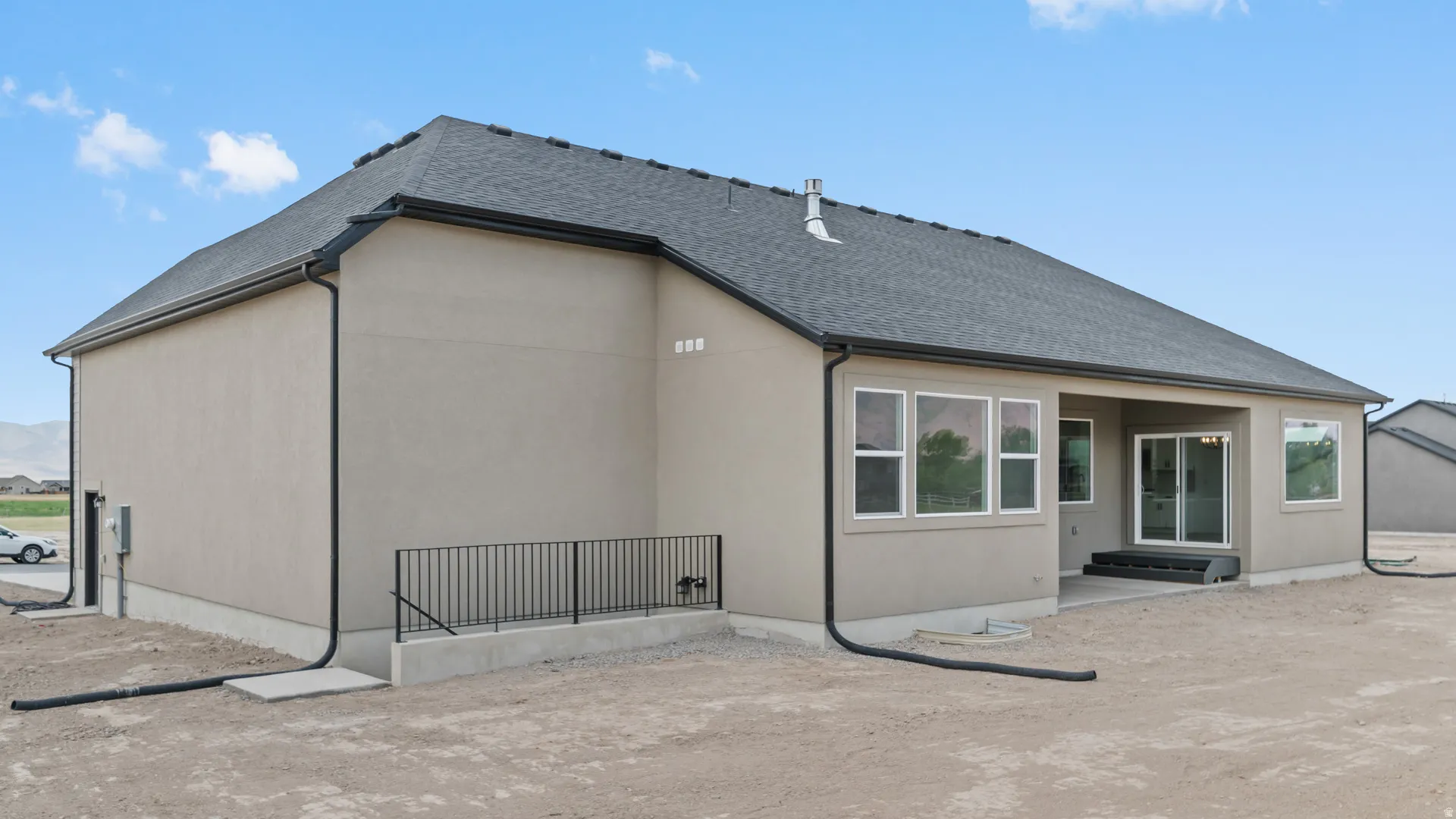 Stucco exterior with a dark shingle roof and black gutters