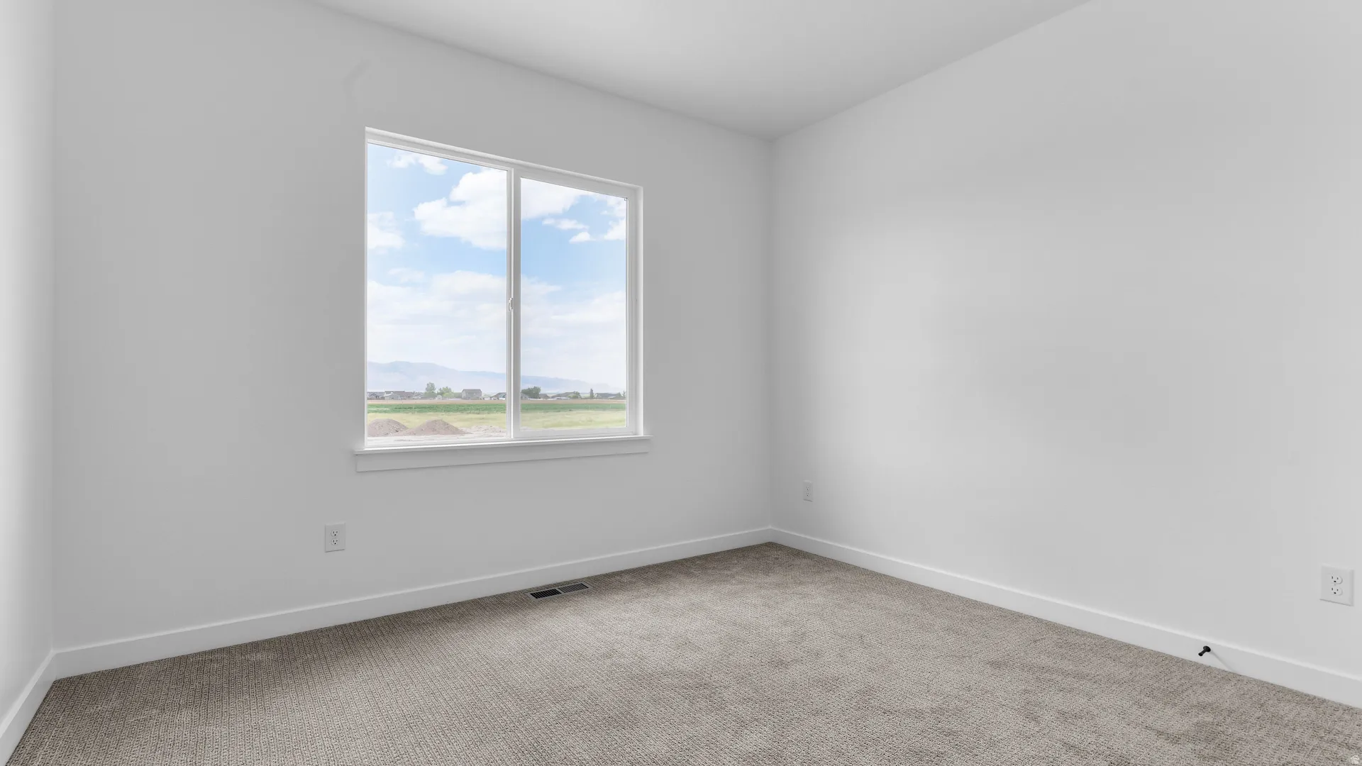 Bright room featuring a large window, neutral carpeting, white baseboards, and a fresh paint finish