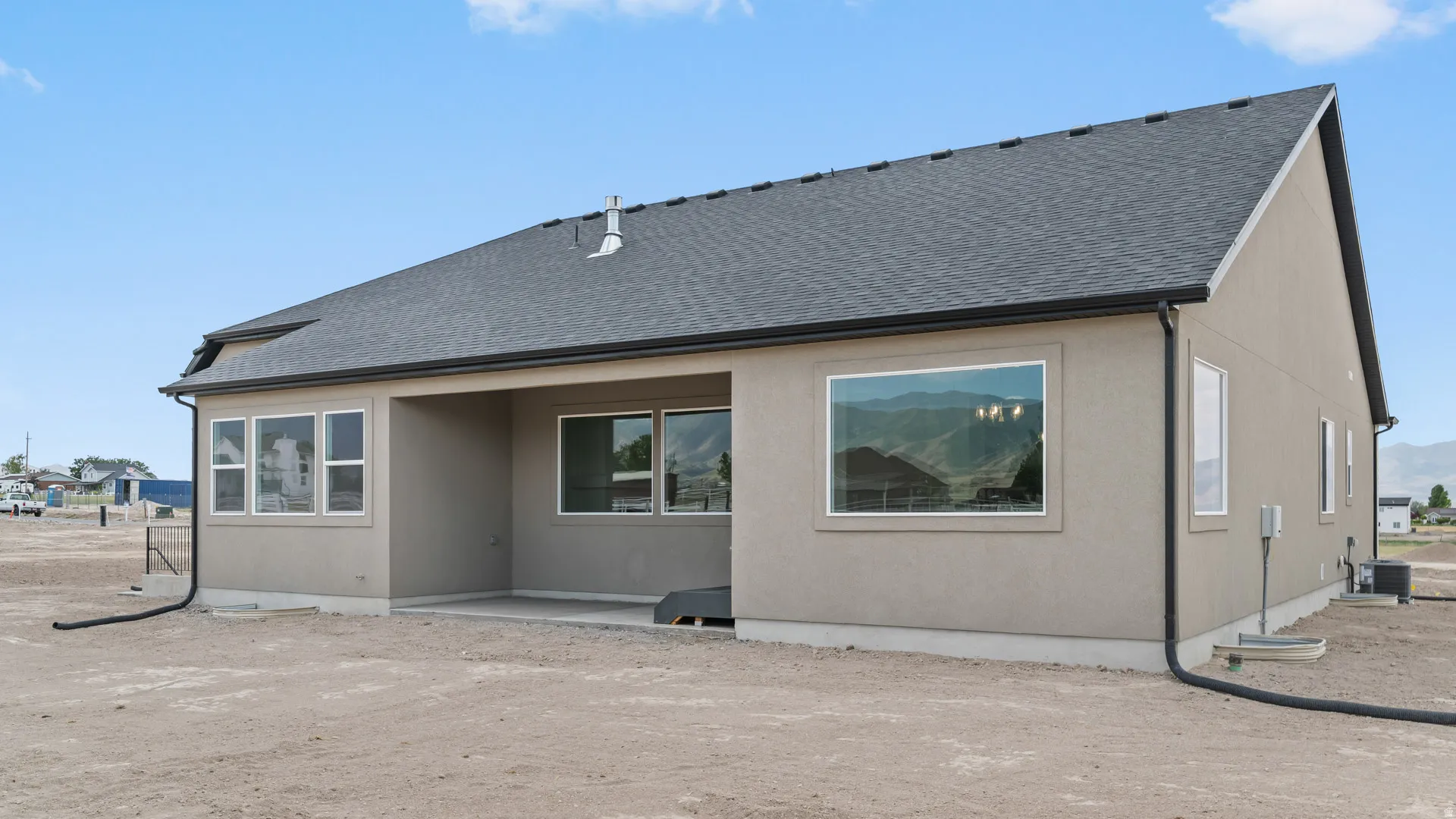 Contemporary stucco exterior with a dark shingle roof and white window trim