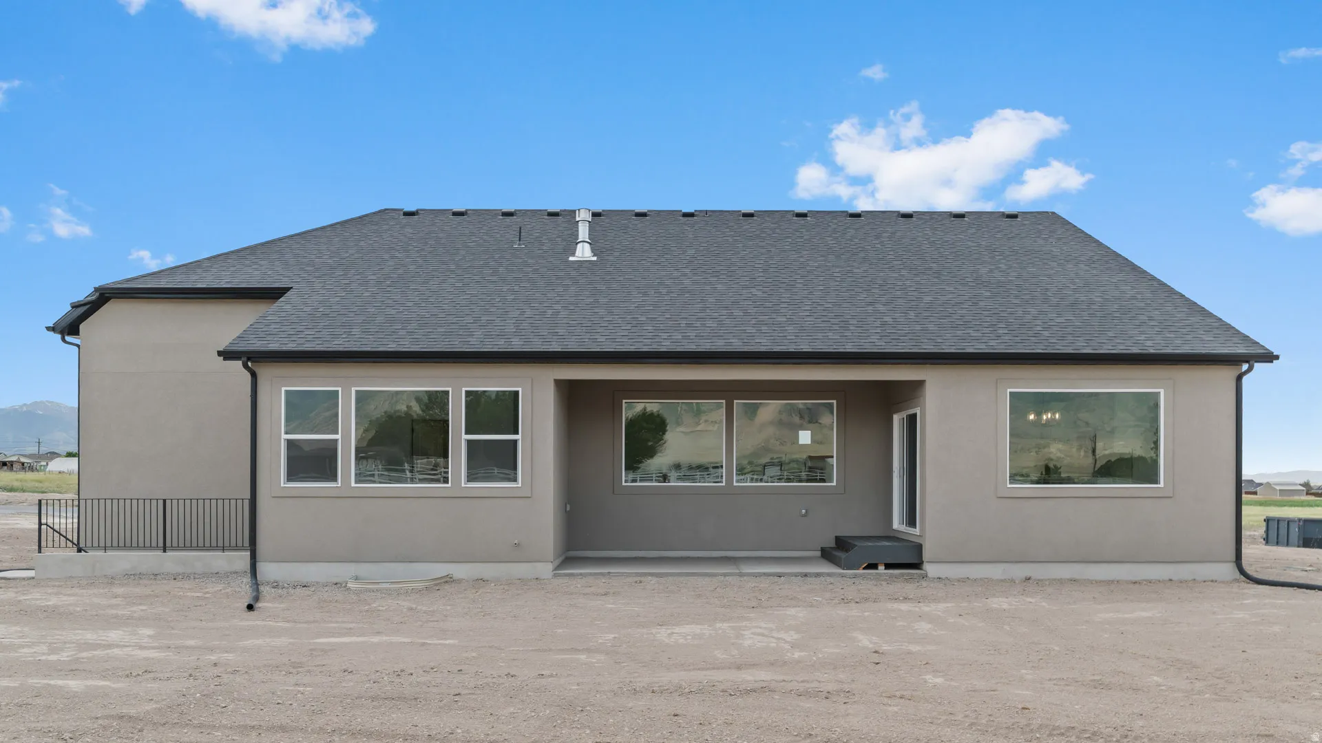 Rear exterior featuring a covered patio, multiple large windows, and a dark shingle roof