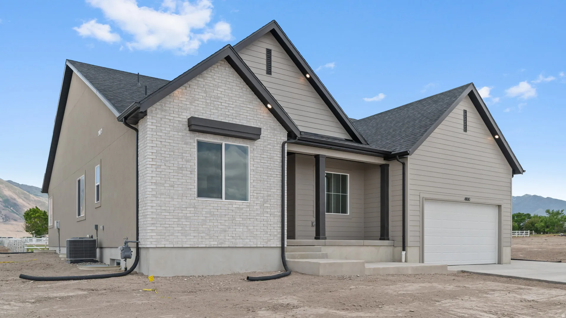 Contemporary exterior featuring light grey brick veneer, horizontal siding, black trim, and a prominent front porch with dark columns
