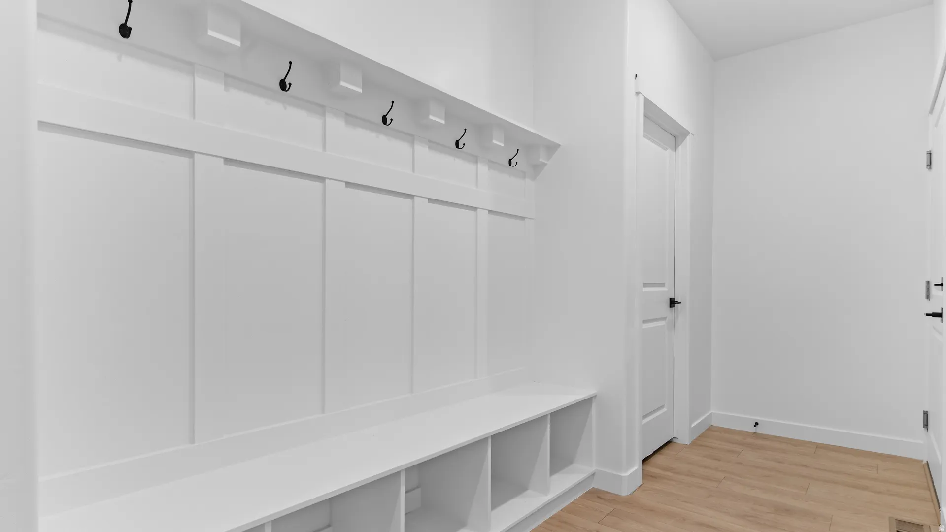 Built-in mudroom bench with cubby storage and upper hooks, featuring white paneling