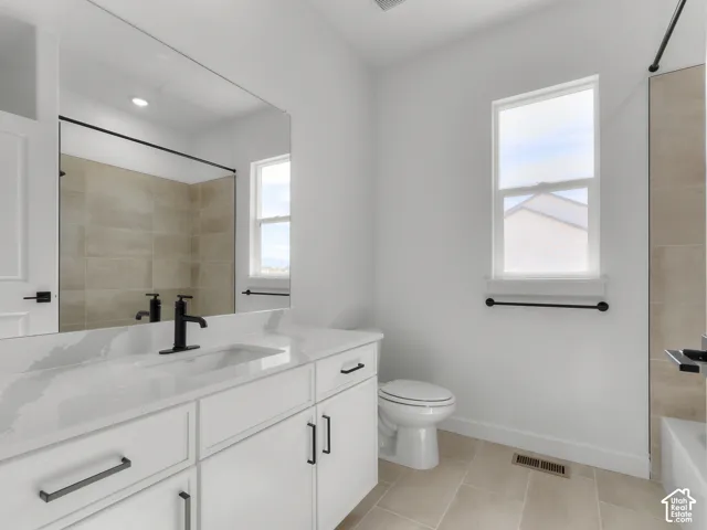 Bathroom featuring white cabinetry, solid-surface countertop with integrated sink, matte black hardware, and tiled shower surround