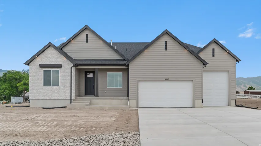 Contemporary exterior featuring a stone facade, horizontal siding, a dark pitched roof, and an expansive concrete driveway