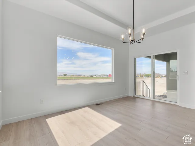 Tray ceiling, wood-finish flooring, large picture window, metal-frame chandelier, and sliding glass door