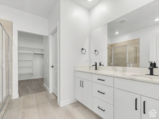 Dual-sink vanity with white cabinetry, light-toned stone countertops, and matte black hardware